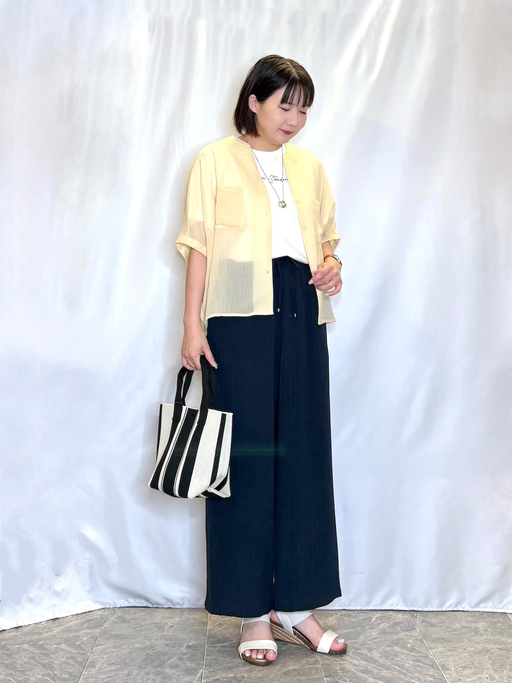 イエロー系のシャツ/ブラウス、ホワイト系のTシャツ/カットソー、ホワイト系のサンダルを着用したレディースの夏コーディネートの2枚目の写真
