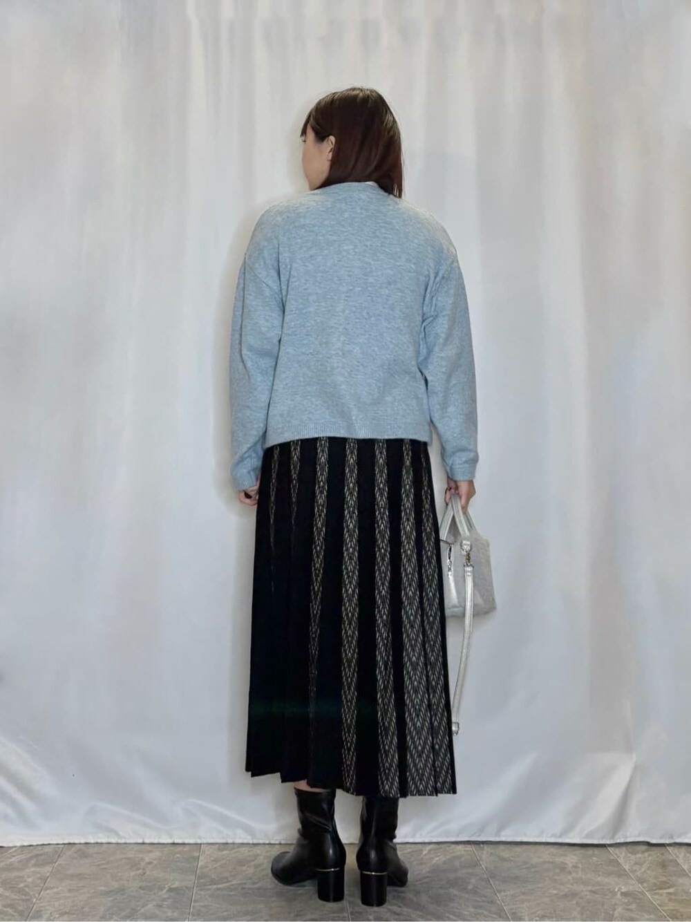 ブルー系のカーディガン/ボレロ、ホワイト系のTシャツ/カットソー、ブラック系のスカートを着用したレディースの秋コーディネートの3枚目の写真