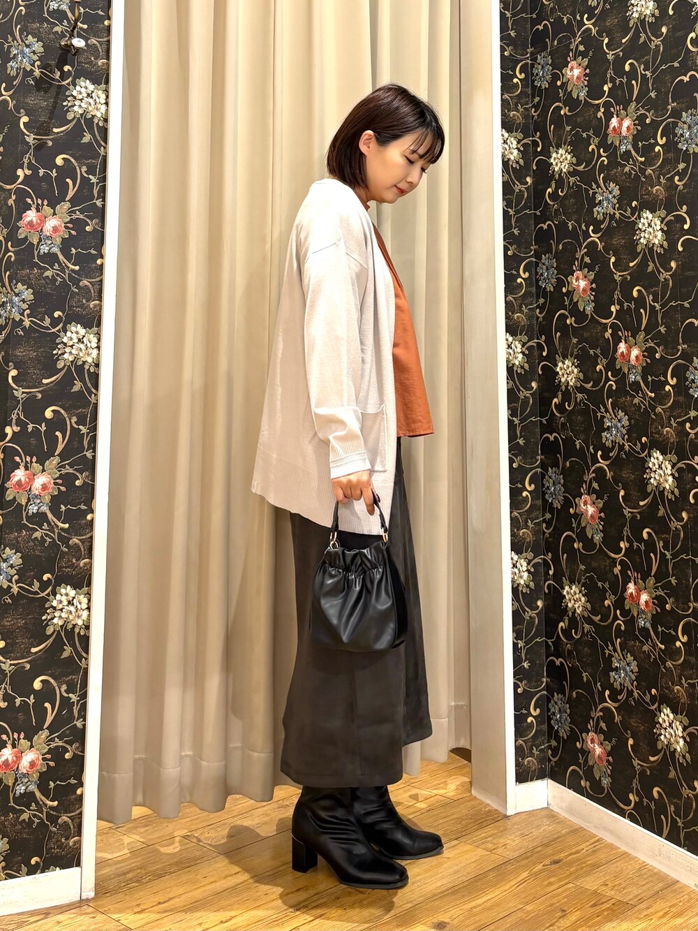 グレー系のカーディガン/ボレロ、オレンジ系のシャツ/ブラウス、グレー系のスカートを着用したレディースの秋コーディネートの2枚目の写真