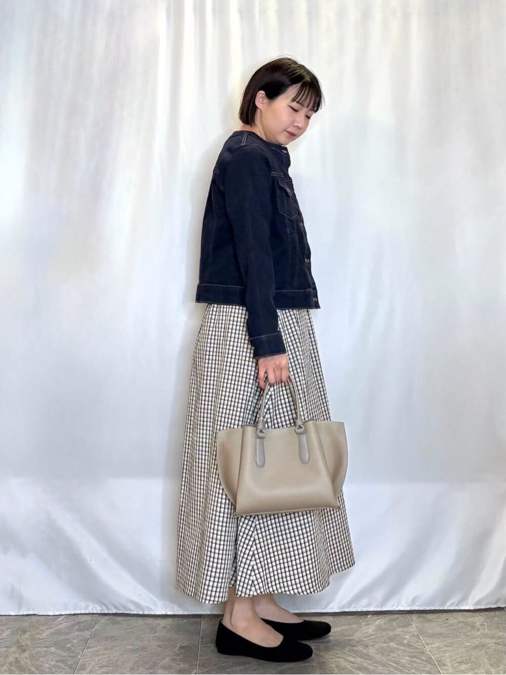 グレー系のワンピース、ブルー系のデニムジャケット、グリーン系のニット/セーターを着用したレディースの春コーディネートの2枚目の写真