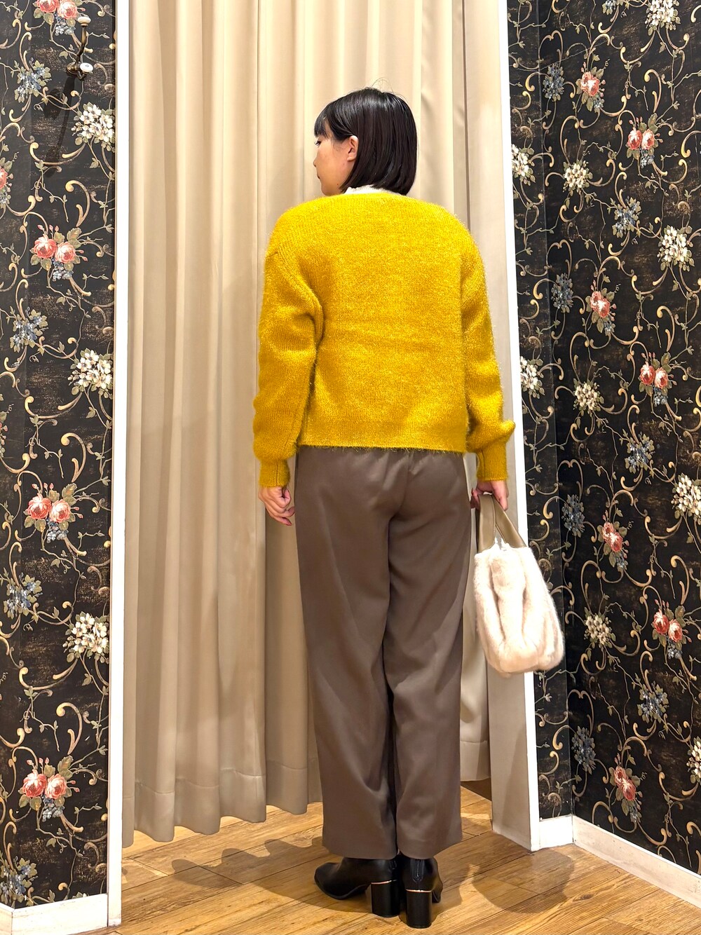 イエロー系のカーディガン/ボレロ、ホワイト系のニット/セーター、ブラウン系のその他パンツを着用したレディースの秋コーディネートの3枚目の写真
