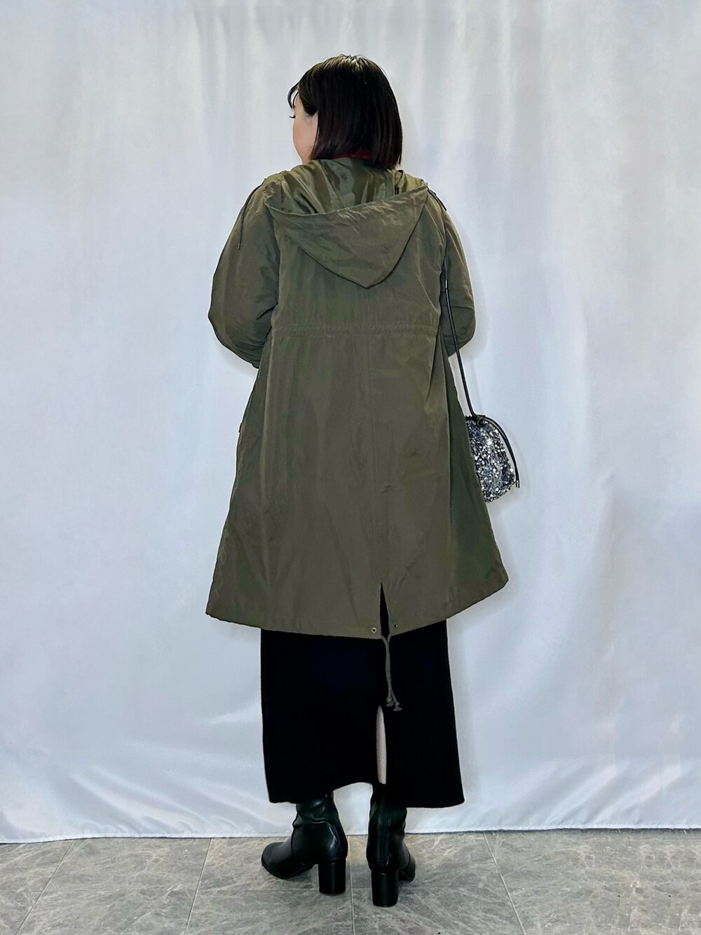 レッド系のニット/セーター、ホワイト系のカーディガン/ボレロ、グリーン系のその他アウターを着用したレディースの冬コーディネートの3枚目の写真