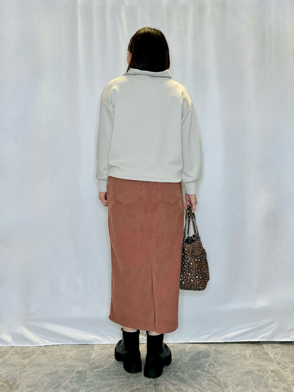 ブラック系のブーツ、グレー系のスウェット、ピンク系のスカートを着用したレディースの秋コーディネートの3枚目の写真