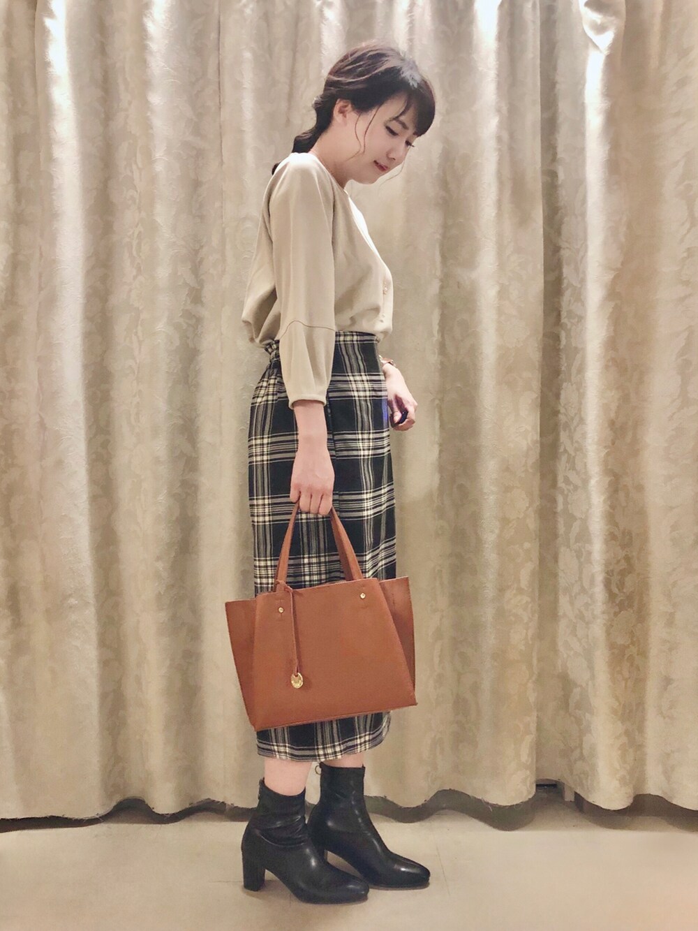 ブラック系のスカート、イエロー系のトートバッグ、ブラック系のブーツを着用したレディースの秋コーディネートの2枚目の写真