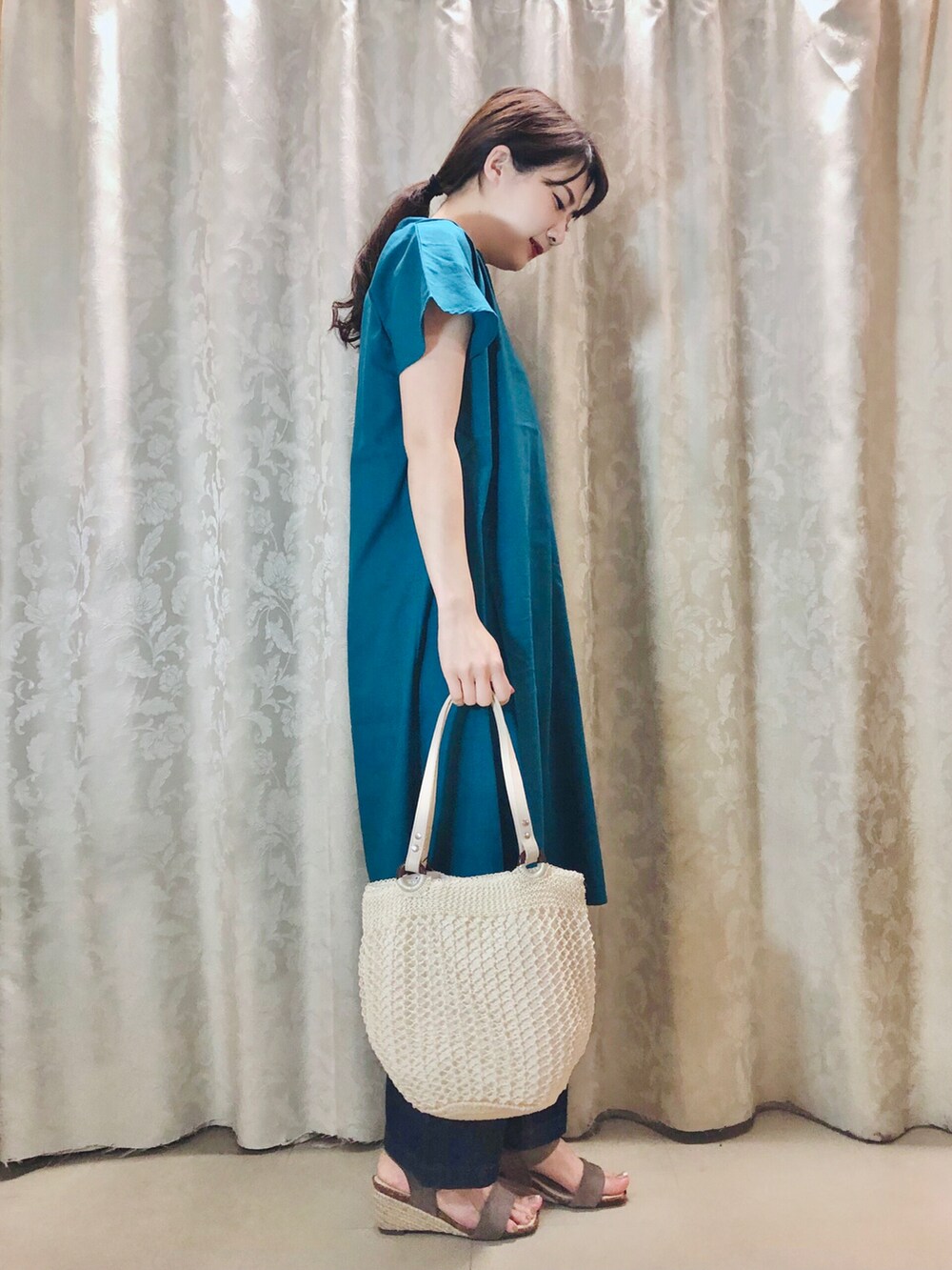 グリーン系のワンピース、ブラウン系のサンダル、ベージュ系のタンクトップを着用したレディースの春コーディネートの2枚目の写真