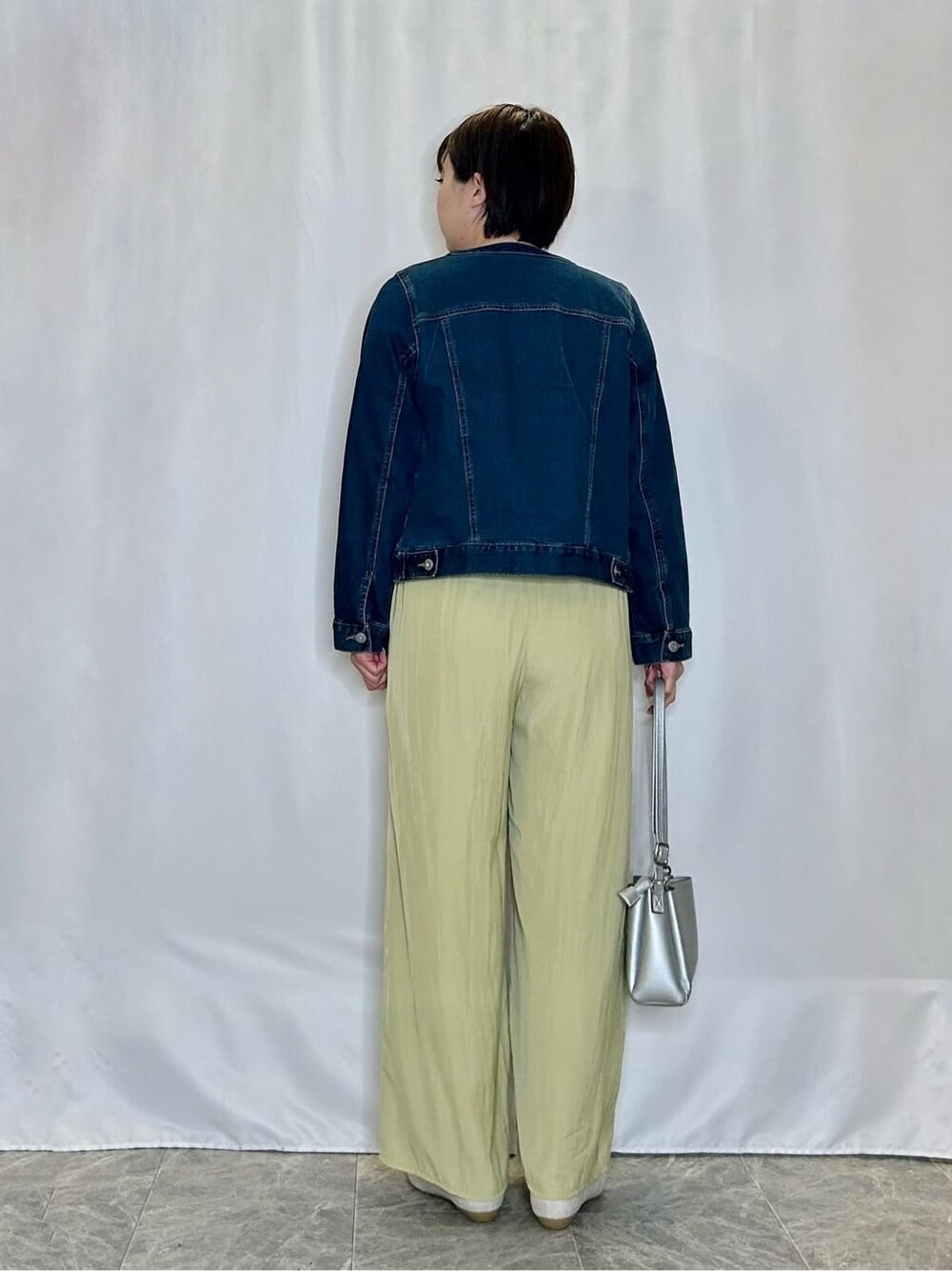 ブルー系のデニムジャケット、ブラック系のニット/セーター、イエロー系のその他パンツを着用したレディースの春コーディネートの3枚目の写真