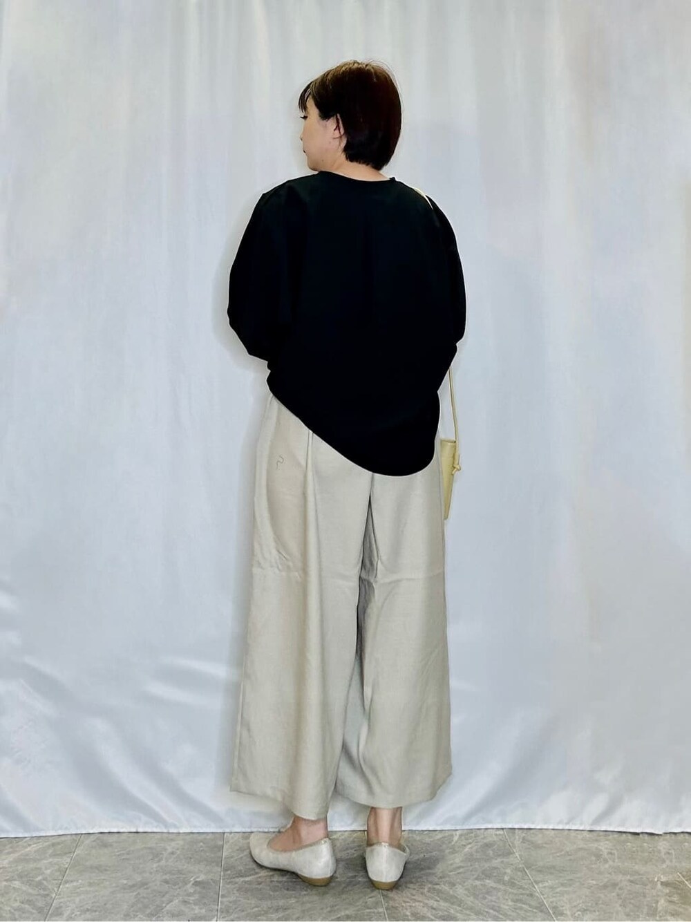 ブラック系のシャツ/ブラウス、ベージュ系のその他パンツ、ゴールド系のその他シューズを着用したレディースの春コーディネートの3枚目の写真