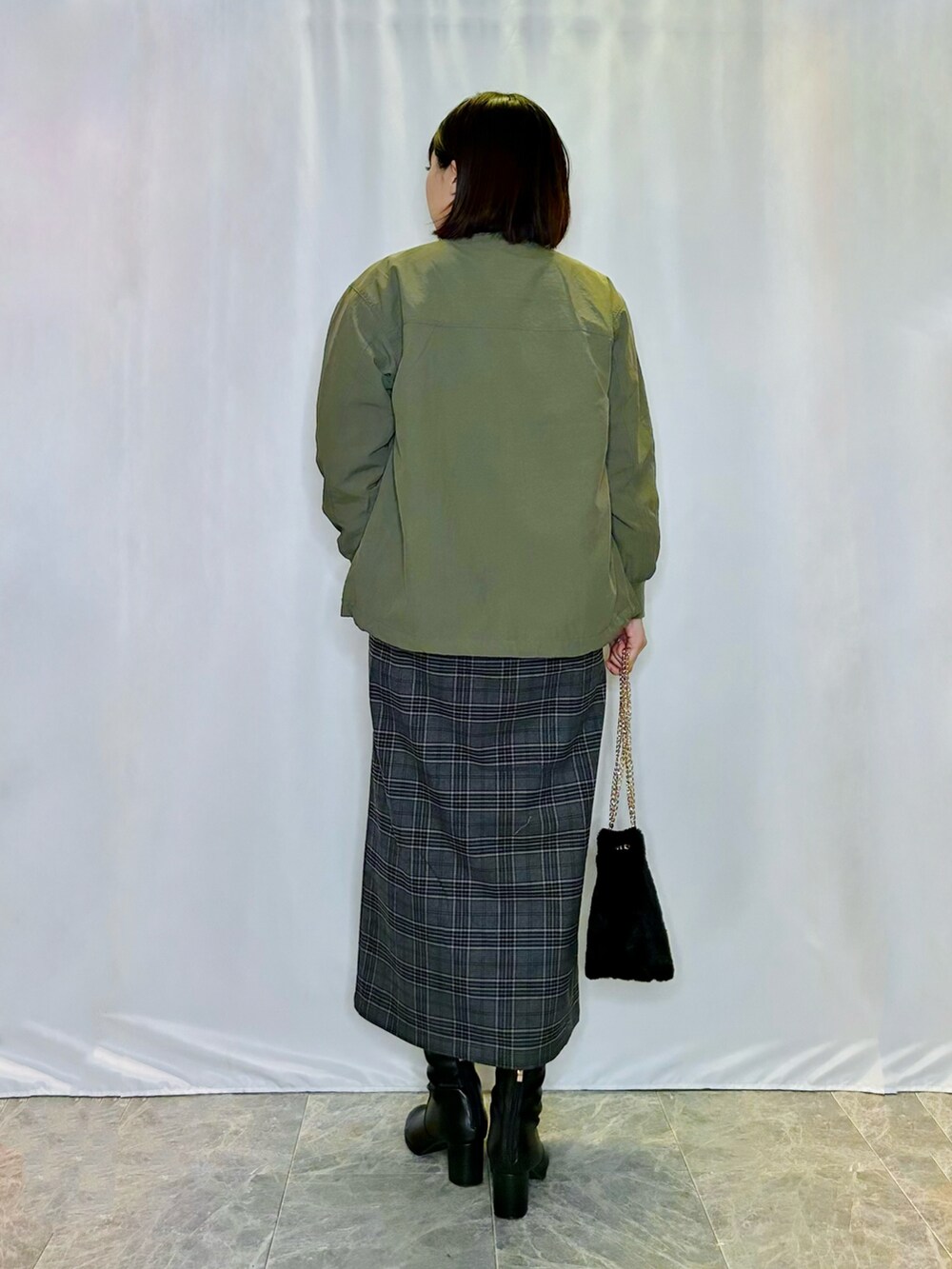 ブラック系のスカート、ブラック系のショルダーバッグ、ブラック系のブーツを着用したレディースの秋コーディネートの3枚目の写真