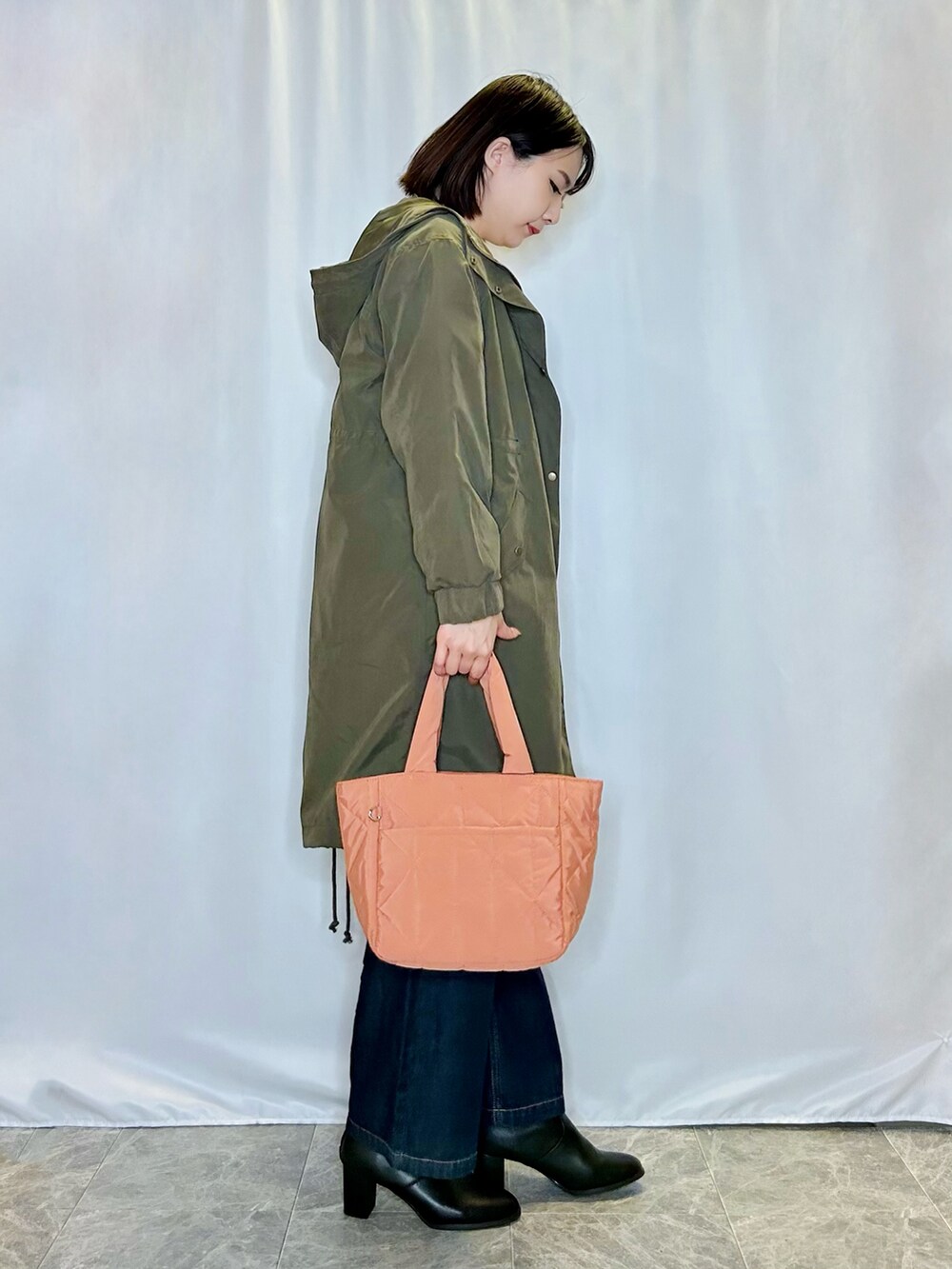 オレンジ系のトートバッグ、ブラック系のブーツ、ブルー系のデニムパンツを着用したレディースの秋コーディネートの2枚目の写真