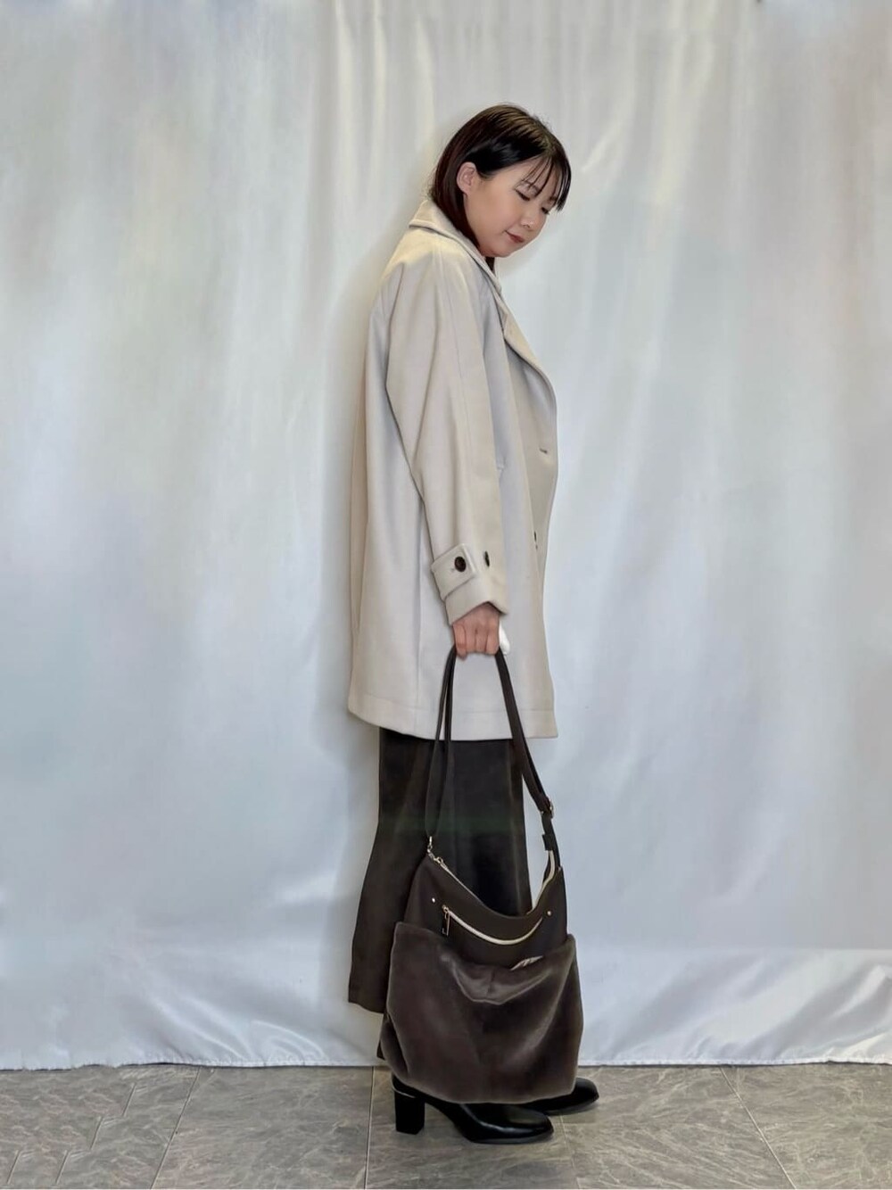 ベージュ系のチェスターコート、ピンク系のニット/セーター、グレー系のスカートを着用したレディースの冬コーディネートの2枚目の写真