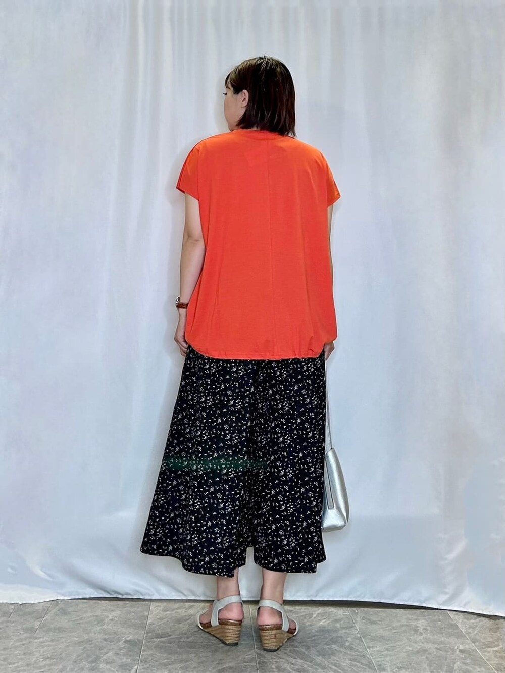 オレンジ系のTシャツ/カットソー、ブラック系のその他パンツ、シルバー系のサンダルを着用したレディースの夏コーディネートの3枚目の写真