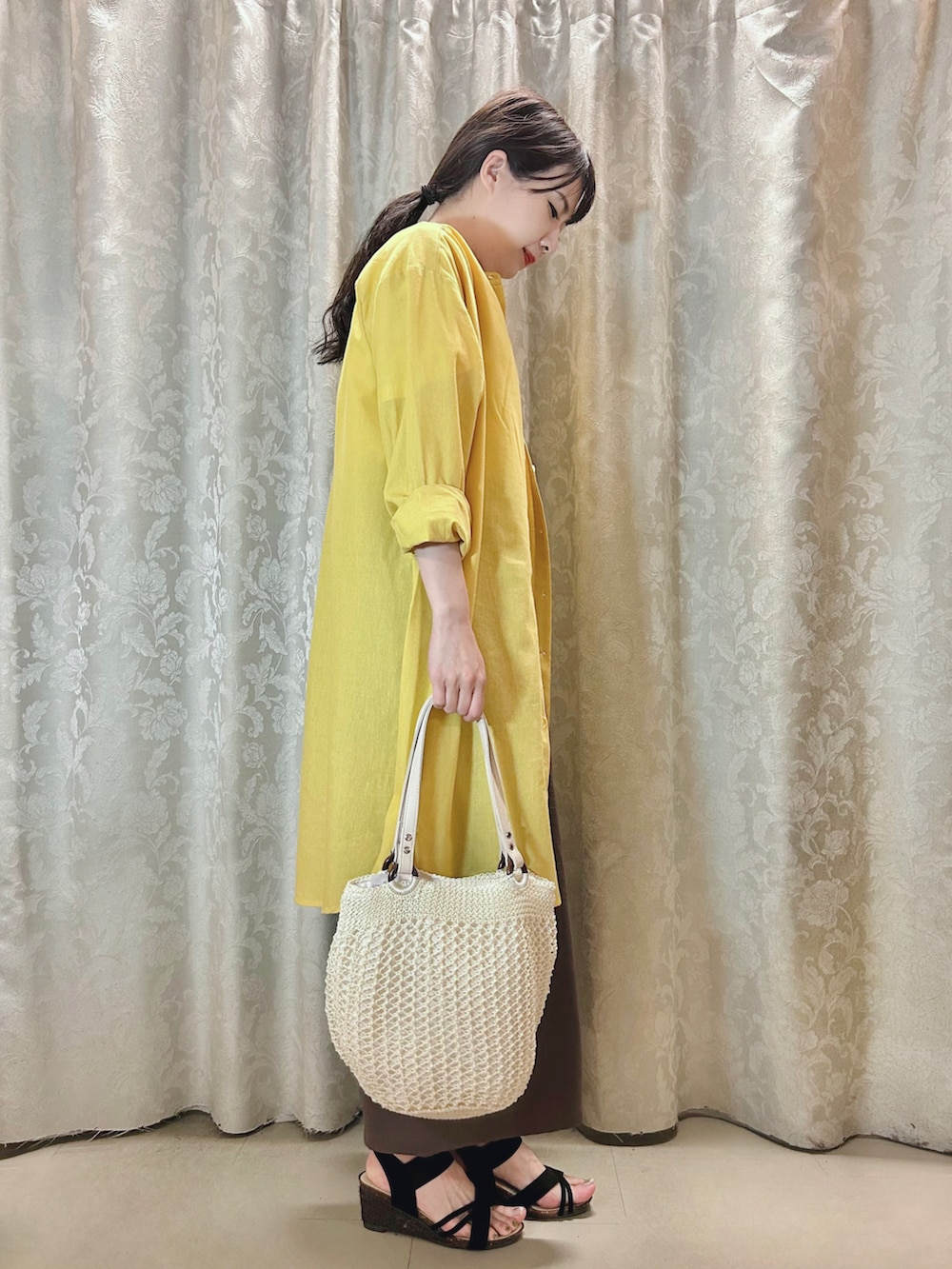 イエロー系のワンピース、ブラウン系のその他パンツ、ホワイト系のトートバッグを着用したレディースの春コーディネートの2枚目の写真