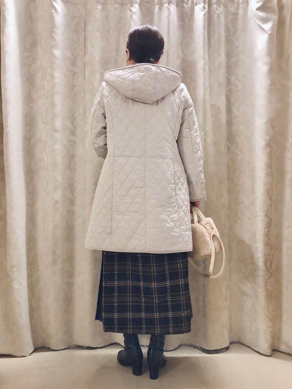 イエロー系のニット/セーター、ブルー系のスカート、ブラック系のブーツを着用したレディースの秋コーディネートの3枚目の写真