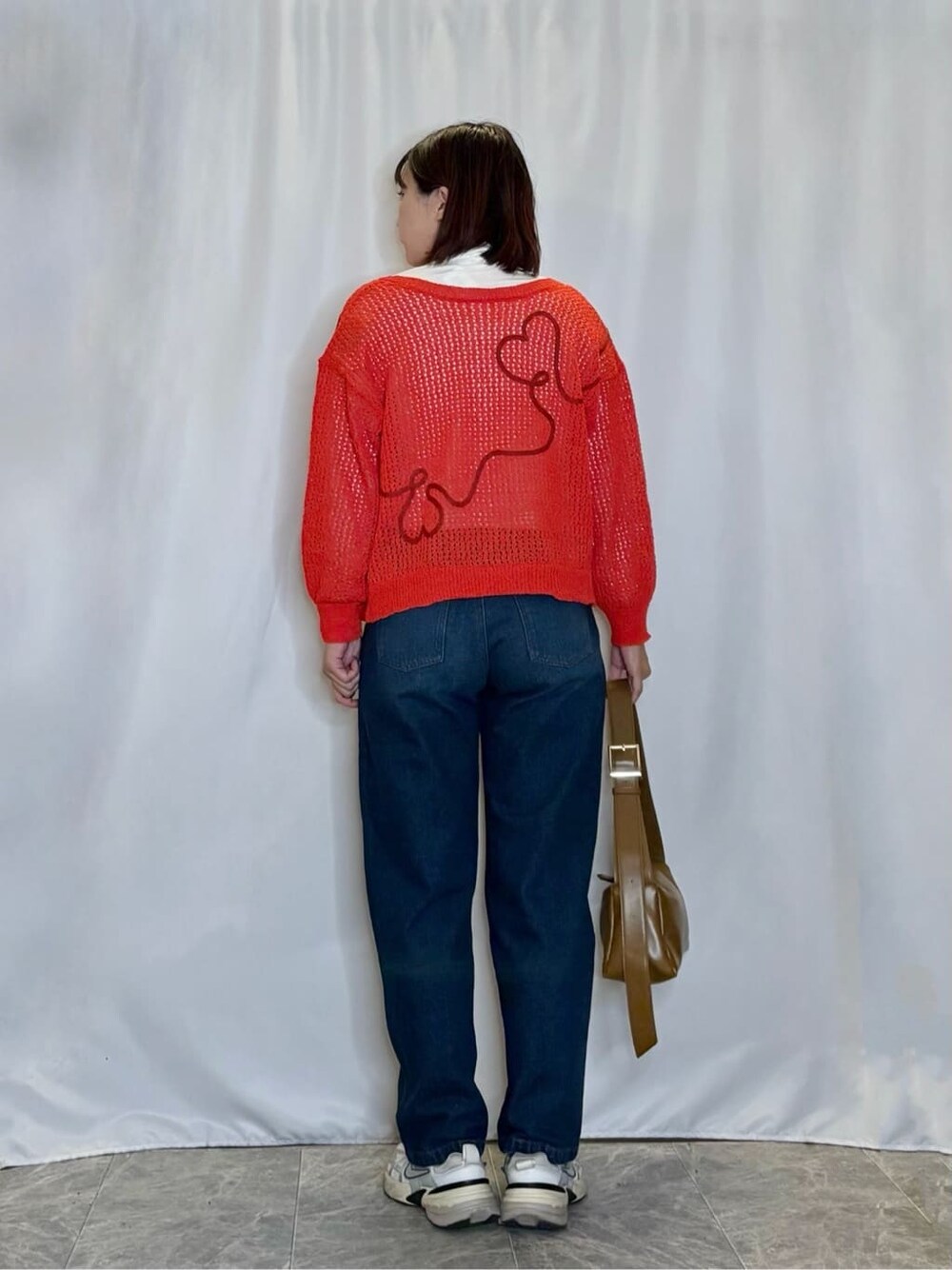 レッド系のカーディガン/ボレロ、ホワイト系のTシャツ/カットソー、ブルー系のデニムパンツを着用したレディースの秋コーディネートの3枚目の写真