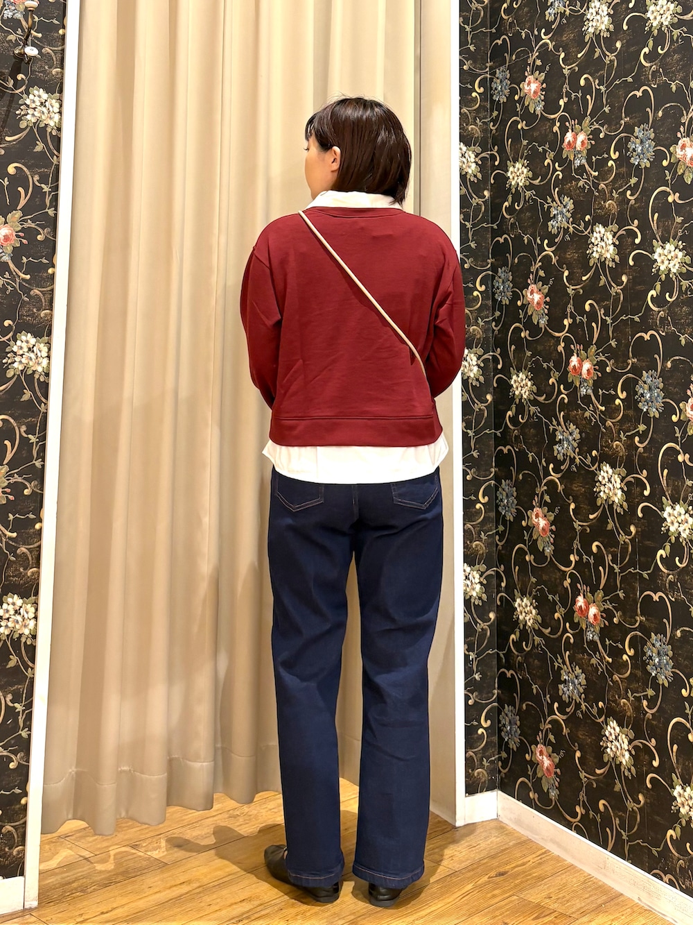 レッド系のTシャツ/カットソー、ブルー系のデニムパンツ、ベージュ系のショルダーバッグを着用したレディースの秋コーディネートの3枚目の写真