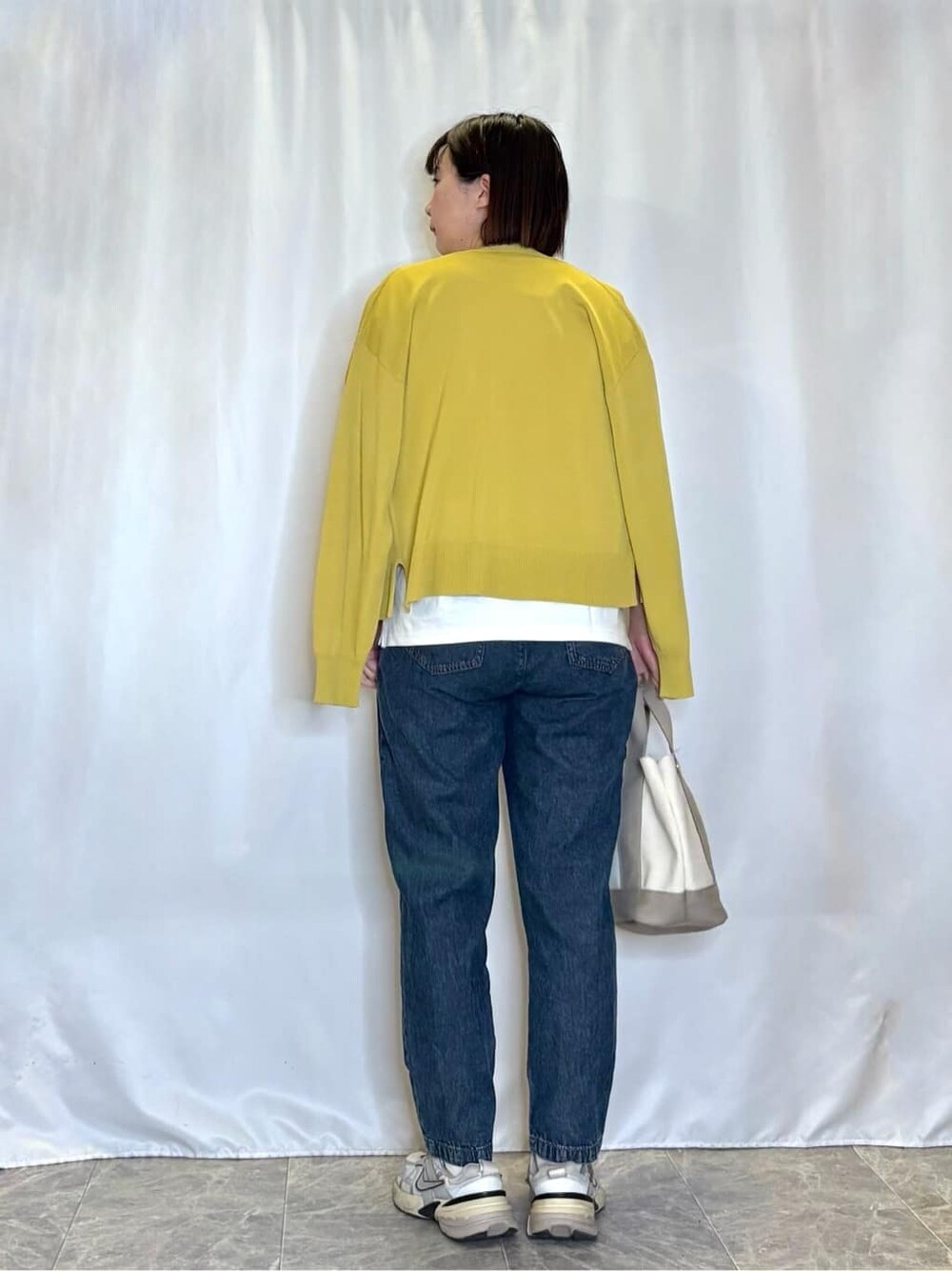 イエロー系のカーディガン/ボレロ、ホワイト系のTシャツ/カットソー、ブルー系のデニムパンツを着用したレディースの春コーディネートの3枚目の写真