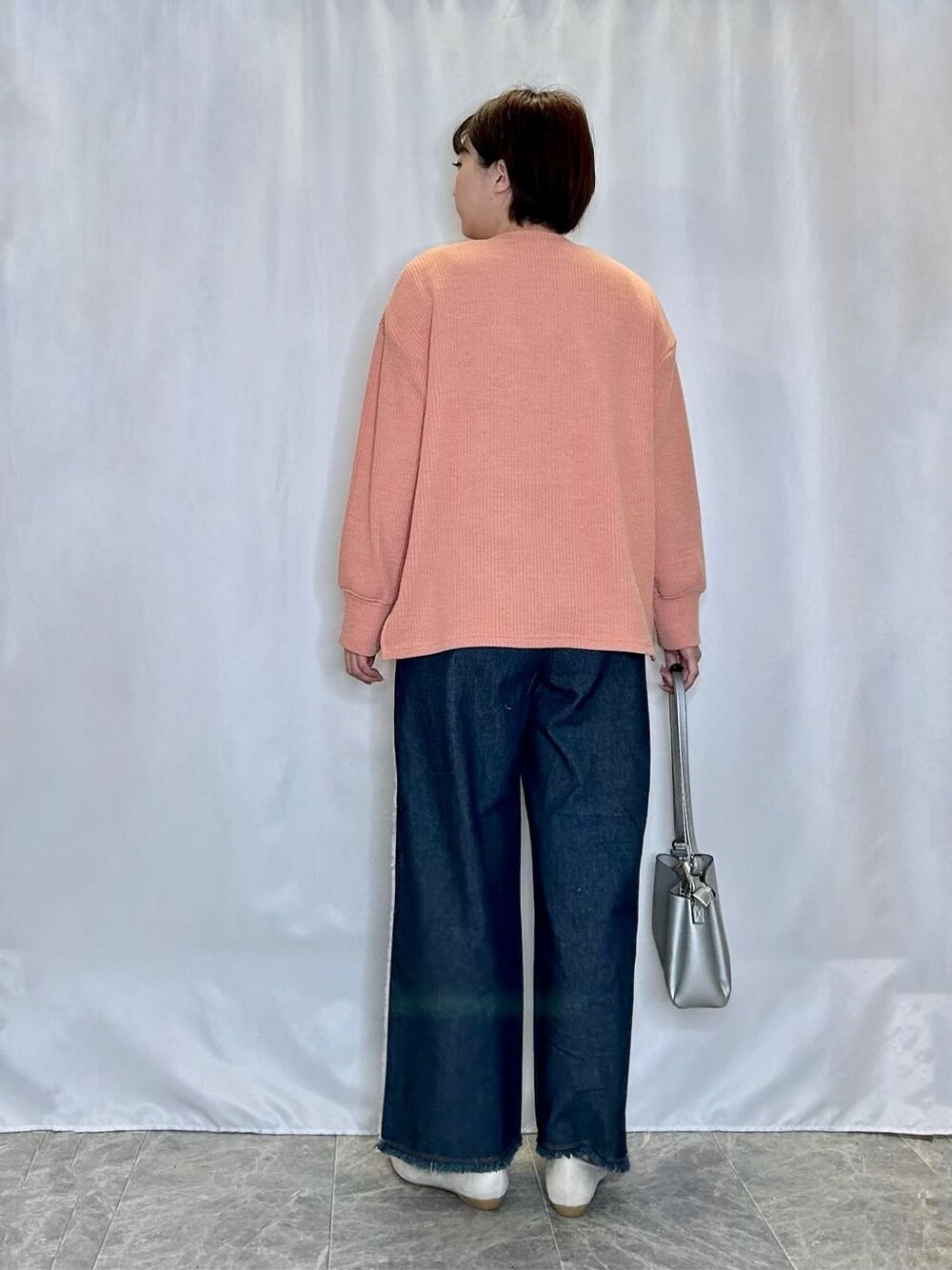 オレンジ系のカーディガン/ボレロ、ホワイト系のタンクトップ、ブルー系のデニムパンツを着用したレディースの春コーディネートの3枚目の写真