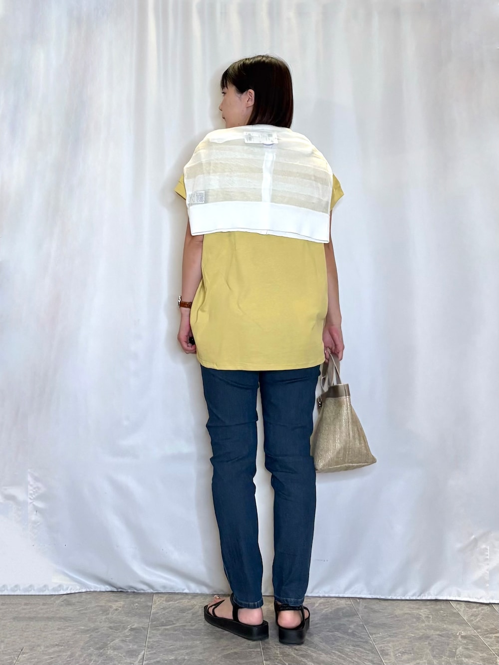 ホワイト系のカーディガン/ボレロ、イエロー系のTシャツ/カットソー、ブルー系のデニムパンツを着用したレディースの夏コーディネートの3枚目の写真