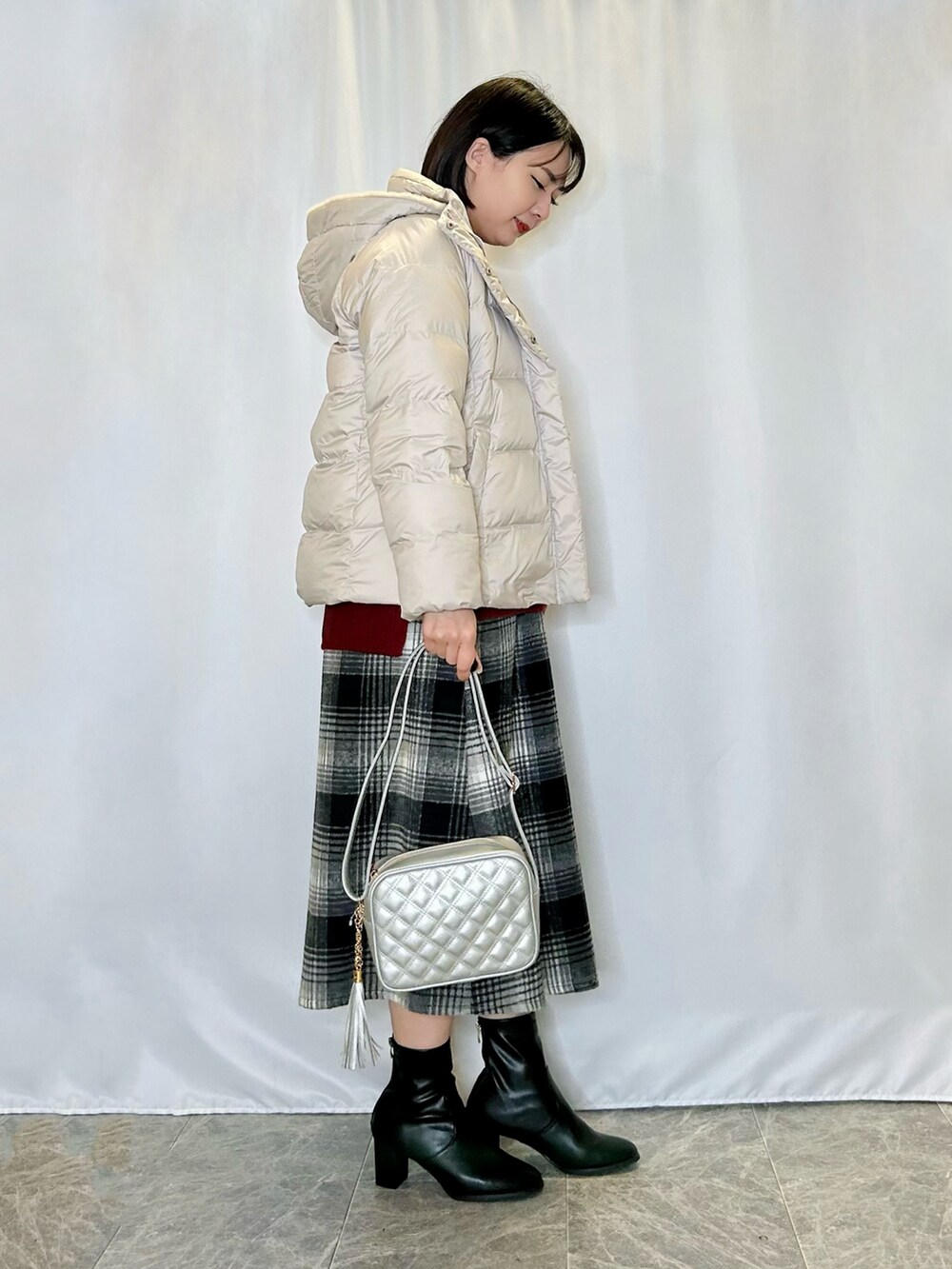 シルバー系のショルダーバッグ、レッド系のニット/セーター、ブラック系のスカートを着用したレディースの冬コーディネートの2枚目の写真