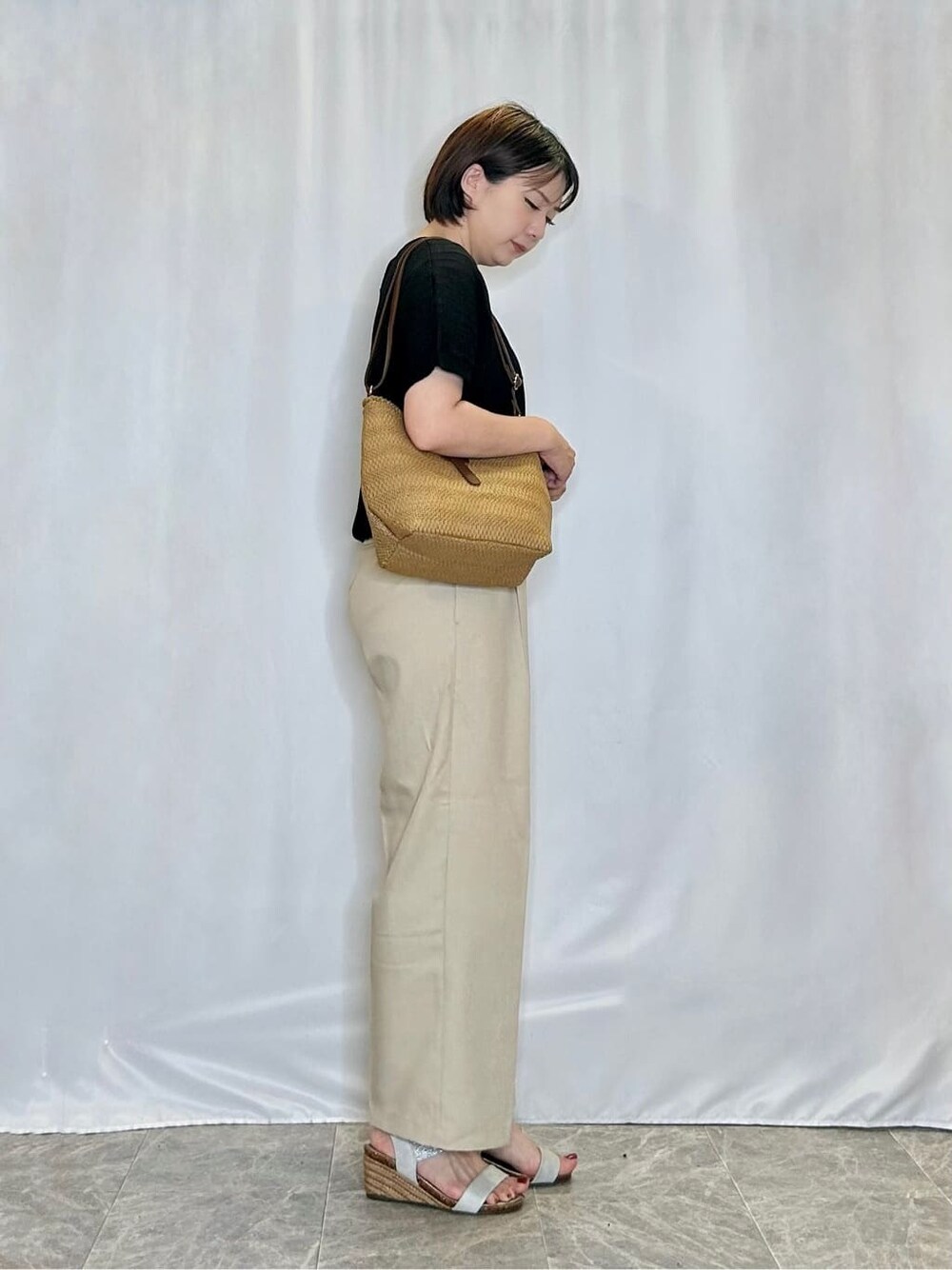 ブラック系のニット/セーター、ベージュ系のその他パンツ、シルバー系のサンダルを着用したレディースの夏コーディネートの2枚目の写真