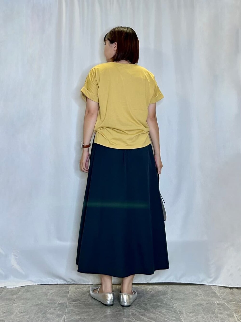 イエロー系のTシャツ/カットソー、ブルー系のスカート、ブラック系のトートバッグを着用したレディースの夏コーディネートの3枚目の写真