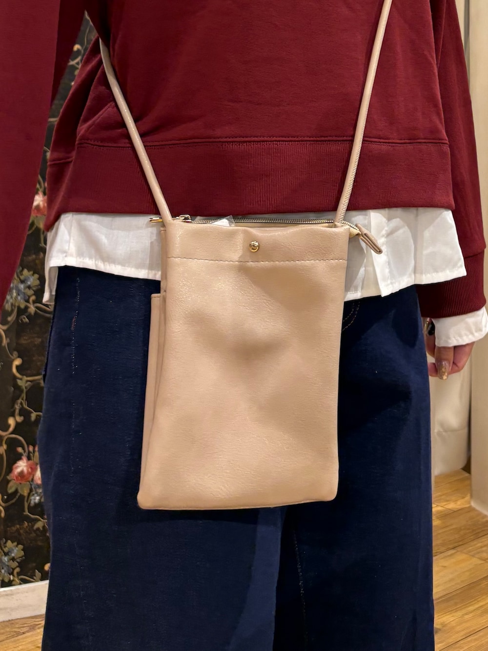 レッド系のTシャツ/カットソー、ブルー系のデニムパンツ、ベージュ系のショルダーバッグを着用したレディースの秋コーディネートの5枚目の写真
