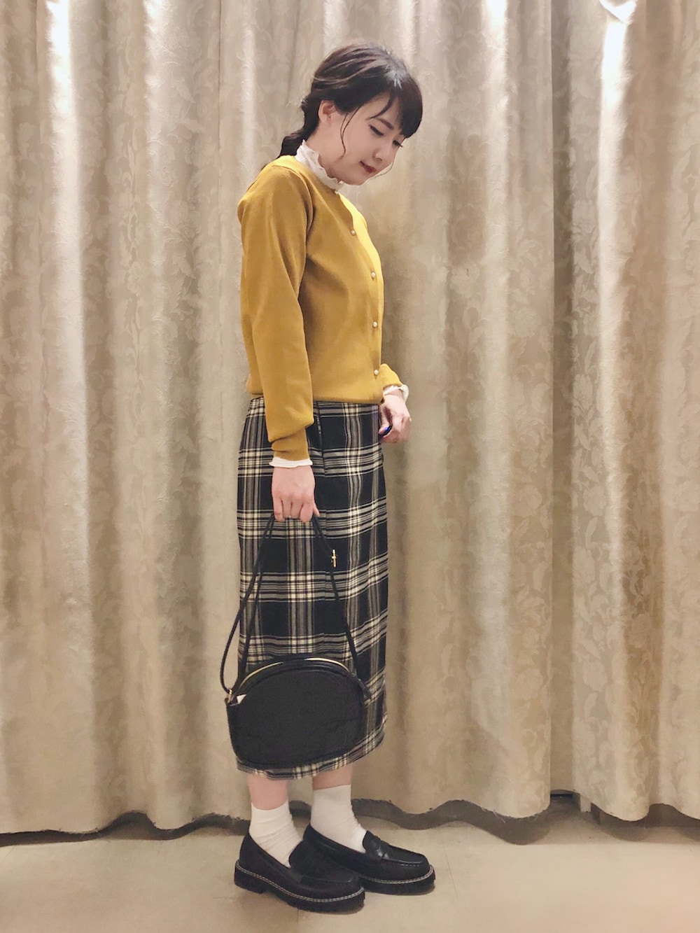 ブラック系のスカート、イエロー系のカーディガン/ボレロ、ホワイト系のTシャツ/カットソーを着用したレディースの秋コーディネートの2枚目の写真