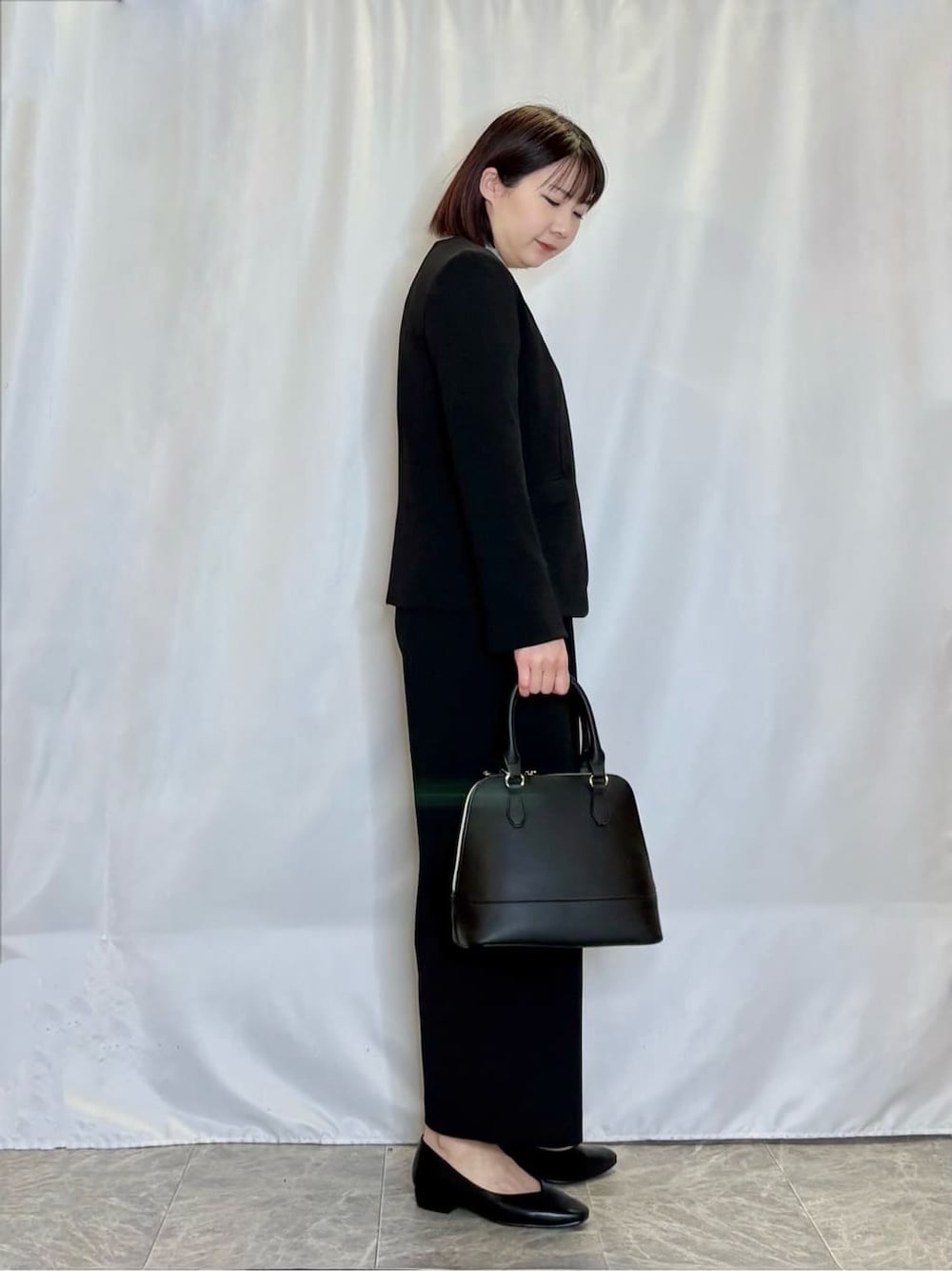 ブラック系のノーカラージャケット、ブラック系のその他パンツ、グレー系のニット/セーターを着用したレディースの冬コーディネートの2枚目の写真