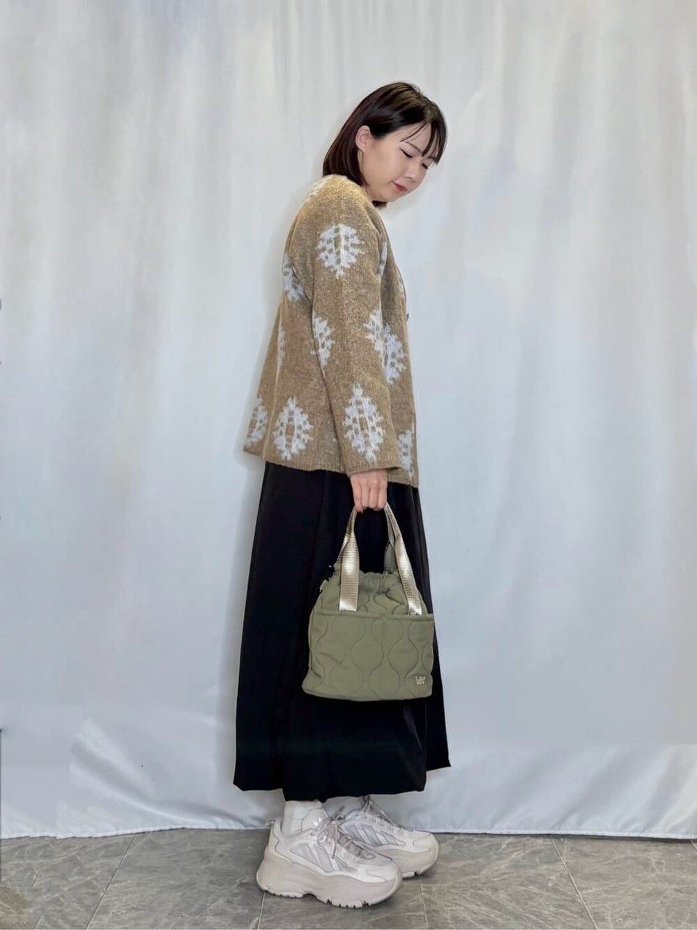 ベージュ系のカーディガン/ボレロ、ホワイト系のTシャツ/カットソー、ブラック系のスカートを着用したレディースの秋コーディネートの2枚目の写真