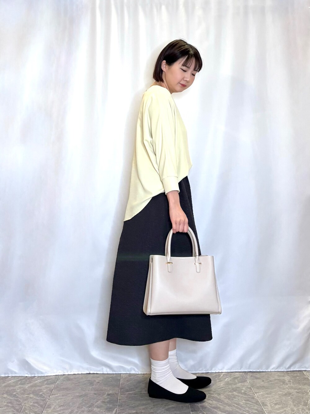 イエロー系のシャツ/ブラウス、グレー系のスカート、ブラック系のパンプスを着用したレディースの春コーディネートの2枚目の写真