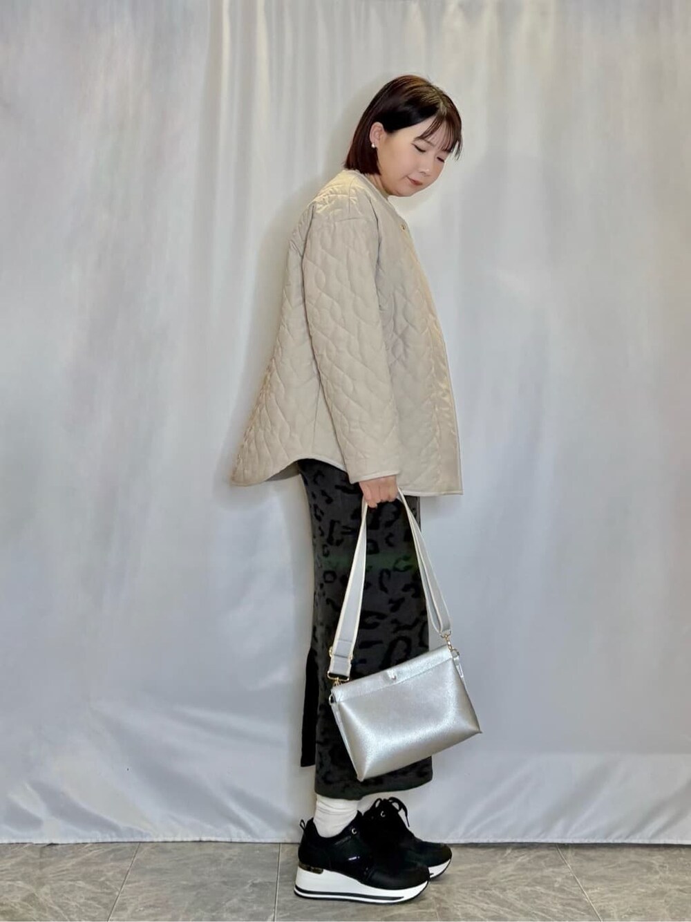 ベージュ系のノーカラージャケット、イエロー系のニット/セーター、グレー系のスカートを着用したレディースの冬コーディネートの2枚目の写真