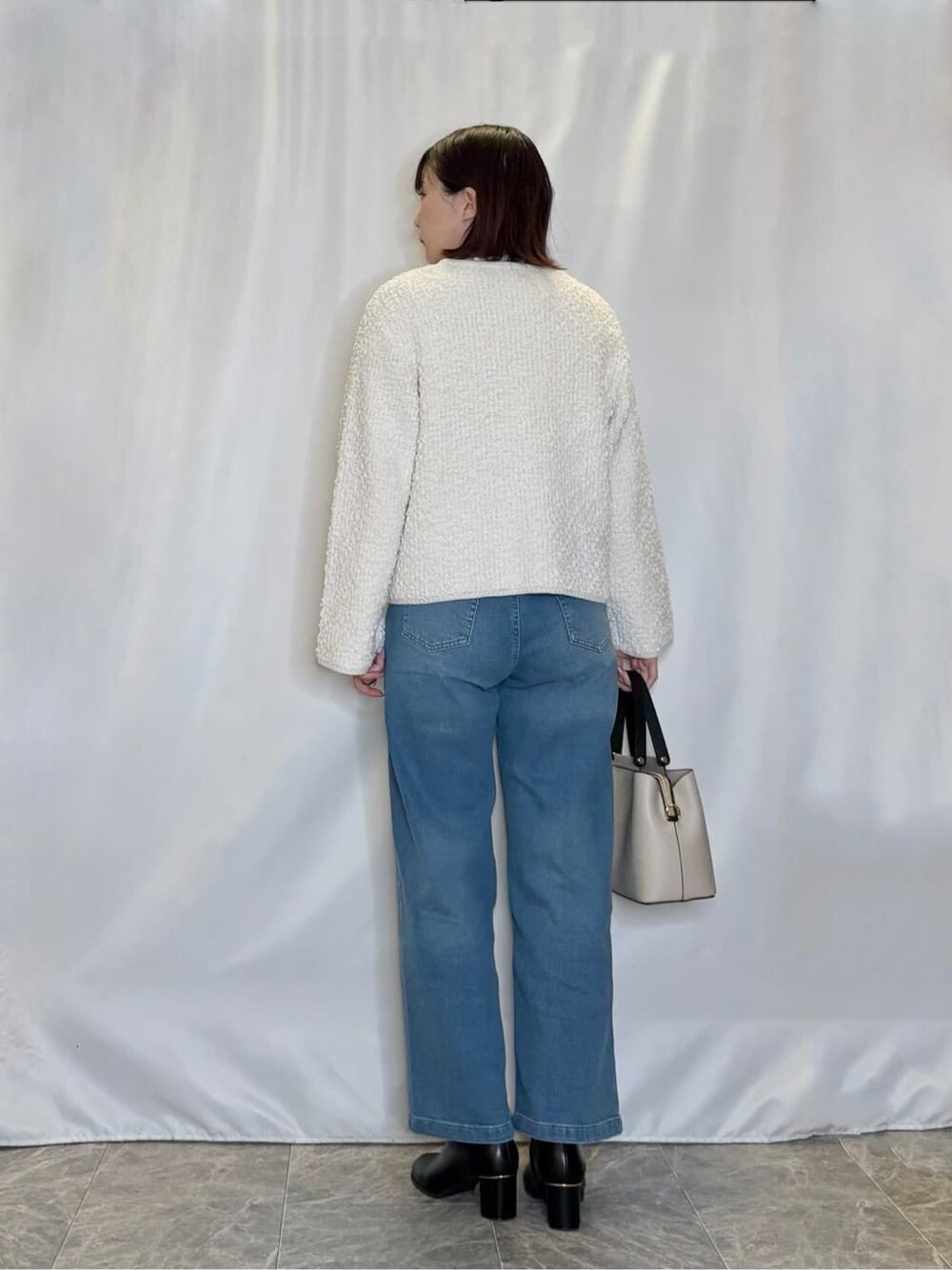ホワイト系のカーディガン/ボレロ、ホワイト系のシャツ/ブラウス、ブルー系のデニムパンツを着用したレディースの冬コーディネートの3枚目の写真