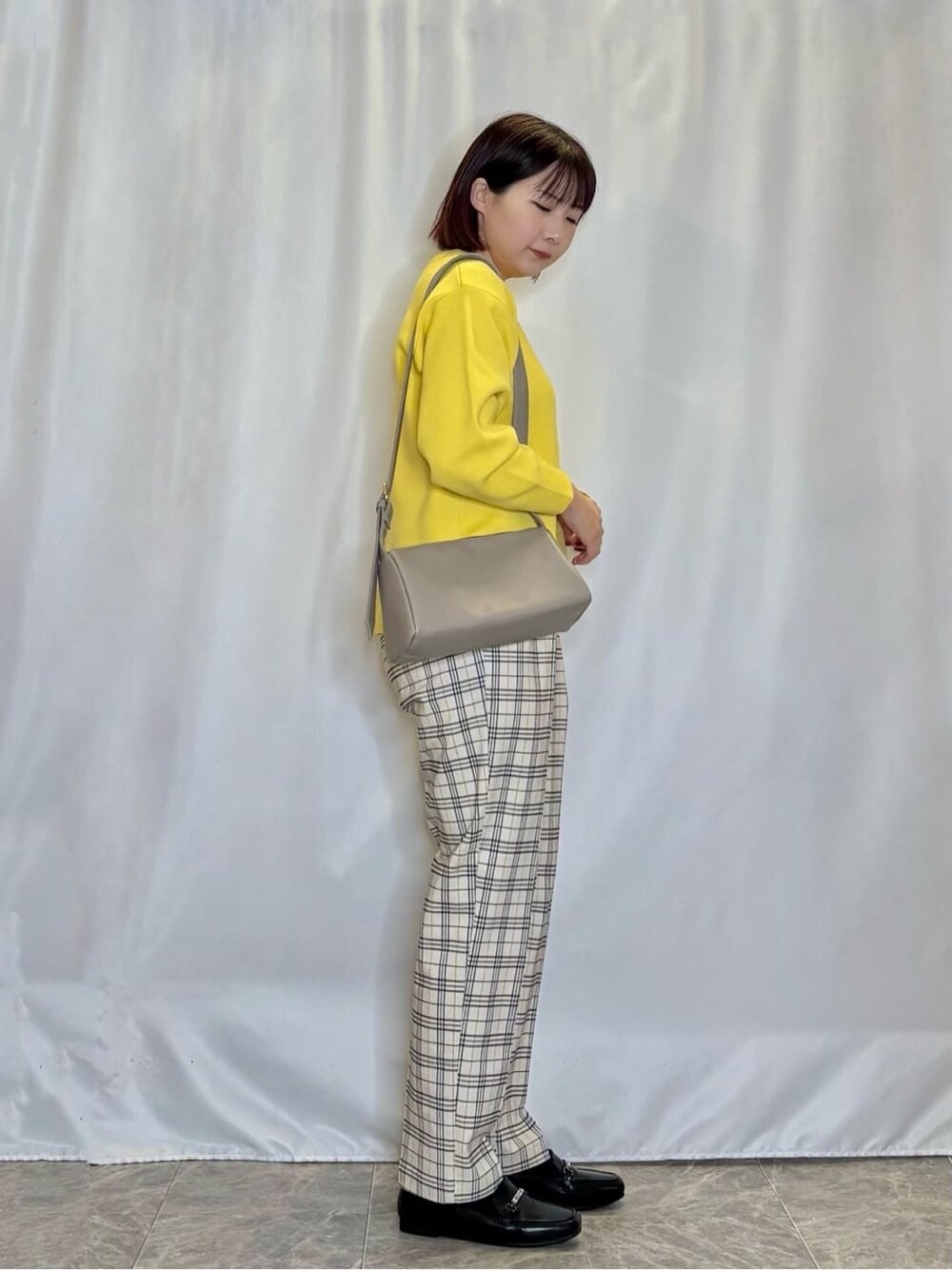 イエロー系のニット/セーター、グレー系のその他パンツ、ブラック系のパンプスを着用したレディースの冬コーディネートの2枚目の写真