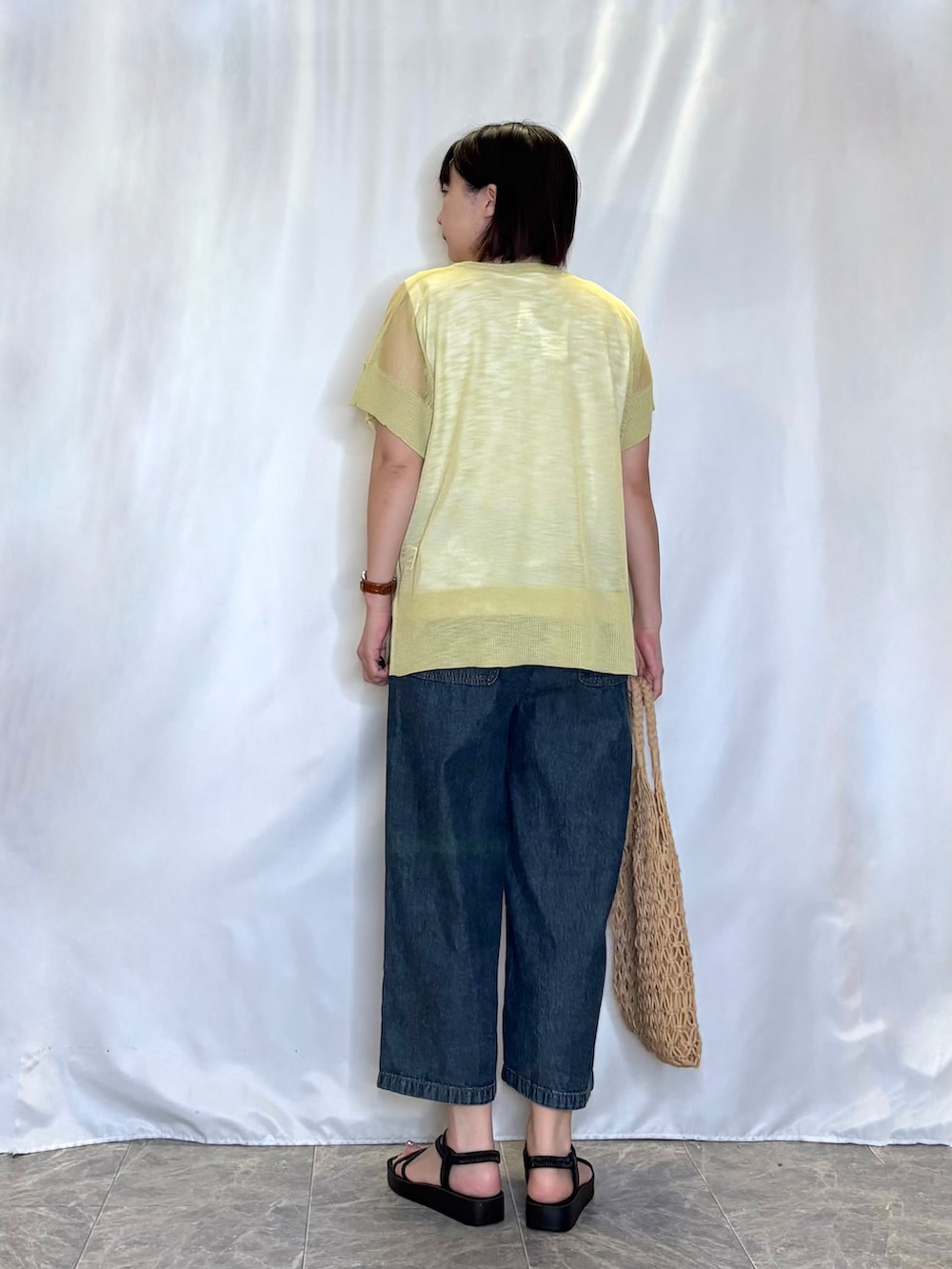 ブルー系のデニムパンツ、イエロー系のトートバッグ、イエロー系のその他トップスを着用したレディースの春コーディネートの3枚目の写真