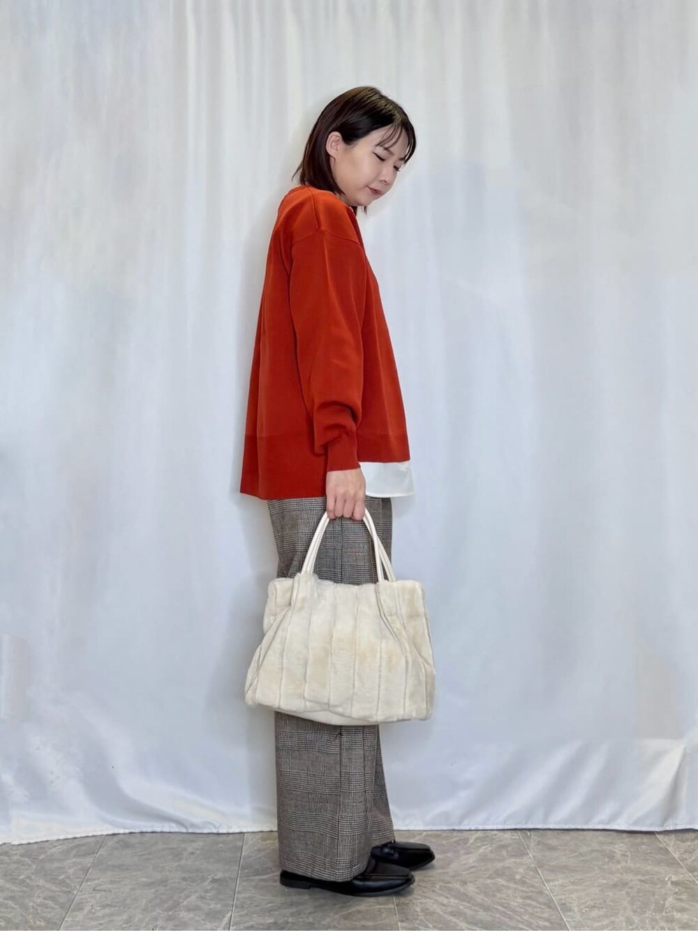 レッド系のニット/セーター、ベージュ系のその他パンツ、ブラック系のその他シューズを着用したレディースの秋コーディネートの2枚目の写真