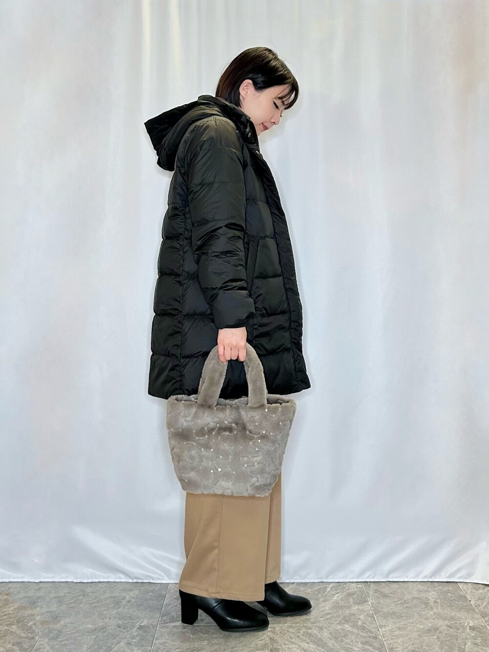 ブラック系のブーツ、ベージュ系のトートバッグ、イエロー系のその他パンツを着用したレディースの冬コーディネートの2枚目の写真