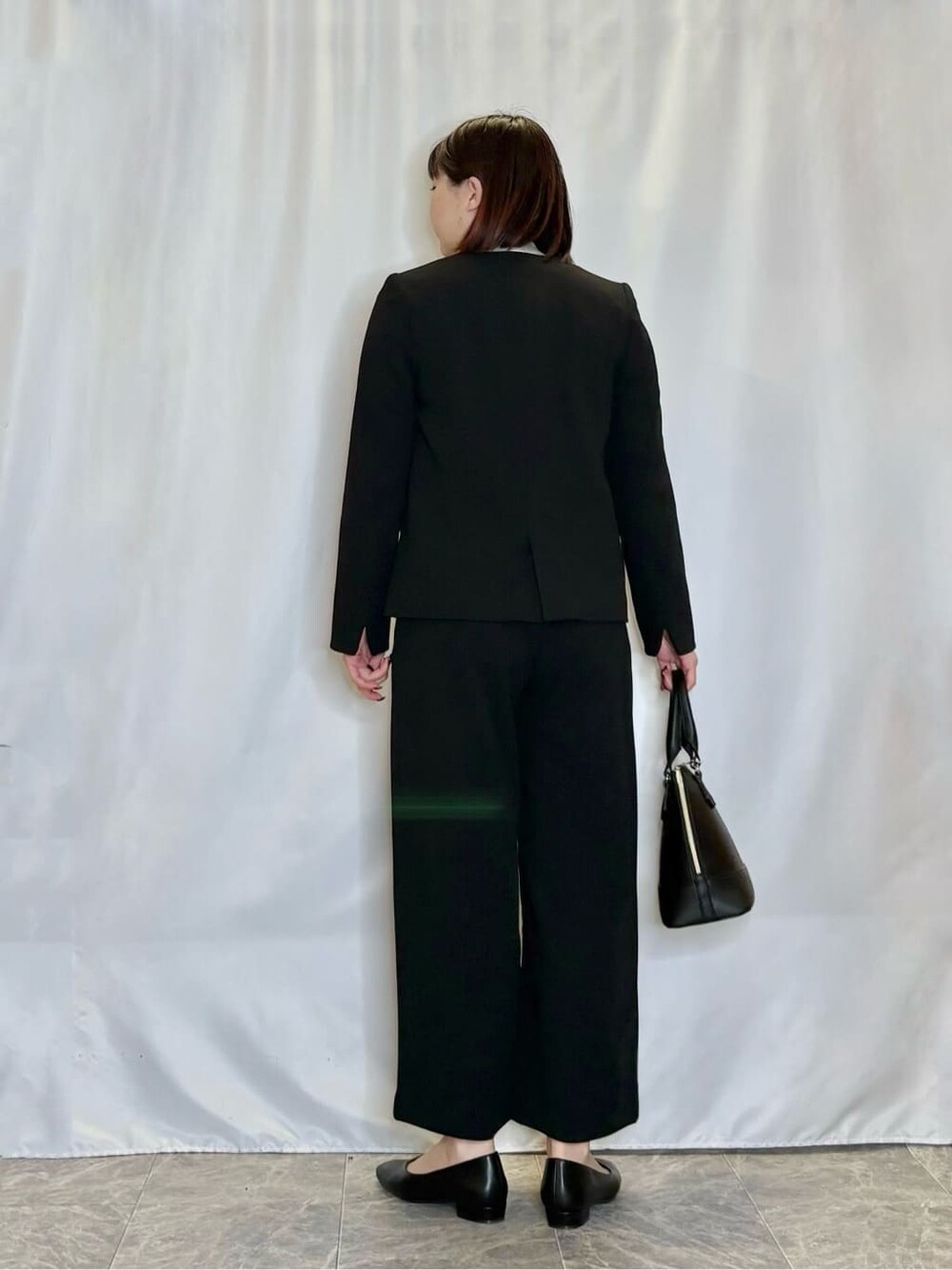 ブラック系のノーカラージャケット、ブラック系のその他パンツ、グレー系のニット/セーターを着用したレディースの冬コーディネートの3枚目の写真