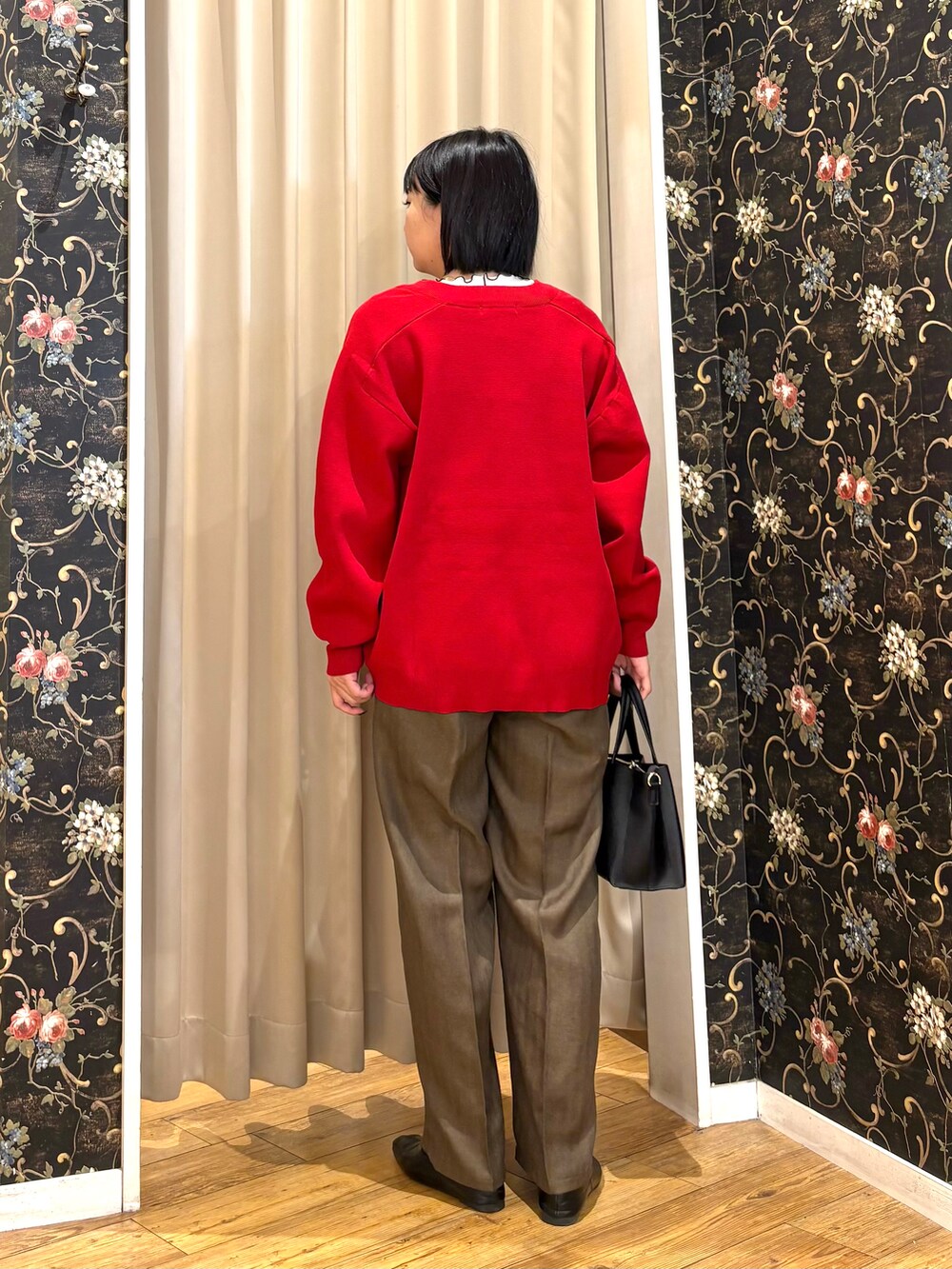 レッド系のカーディガン/ボレロ、ホワイト系のTシャツ/カットソー、ブラック系のトートバッグを着用したレディースの秋コーディネートの3枚目の写真