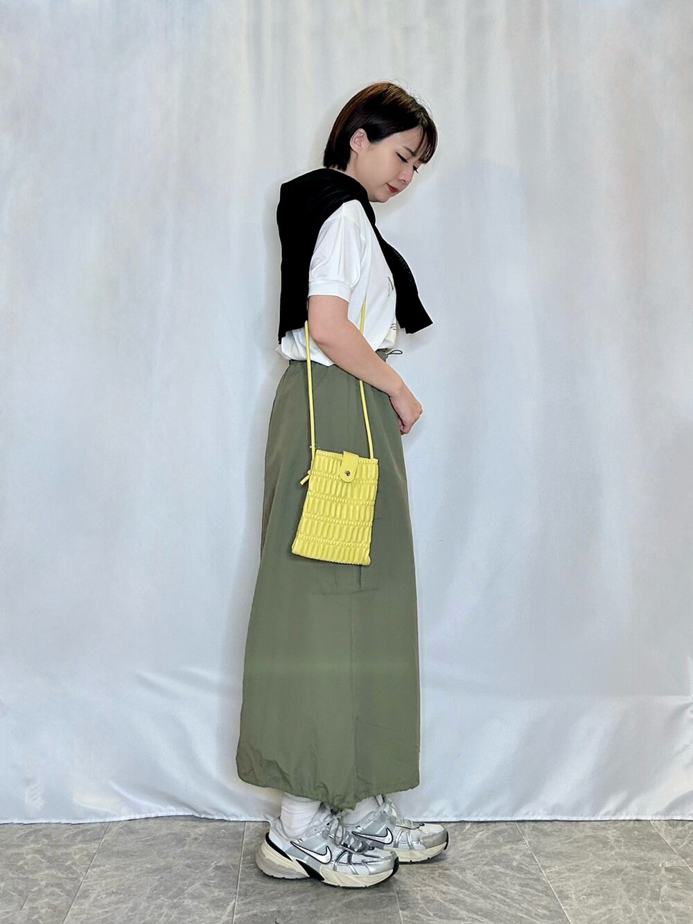グリーン系のスカート、ホワイト系のTシャツ/カットソー、イエロー系のショルダーバッグを着用したレディースの春コーディネートの2枚目の写真