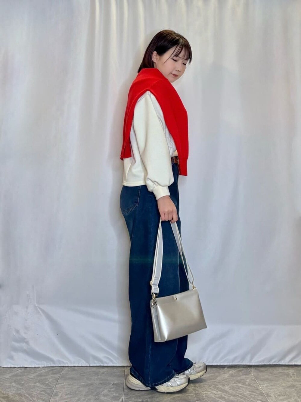 オレンジ系のニット/セーター、ホワイト系のTシャツ/カットソー、ブルー系のデニムパンツを着用したレディースの冬コーディネートの2枚目の写真