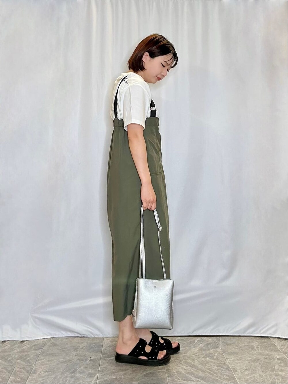 グリーン系のワンピース、ホワイト系のTシャツ/カットソー、ブラック系のサンダルを着用したレディースの夏コーディネートの2枚目の写真