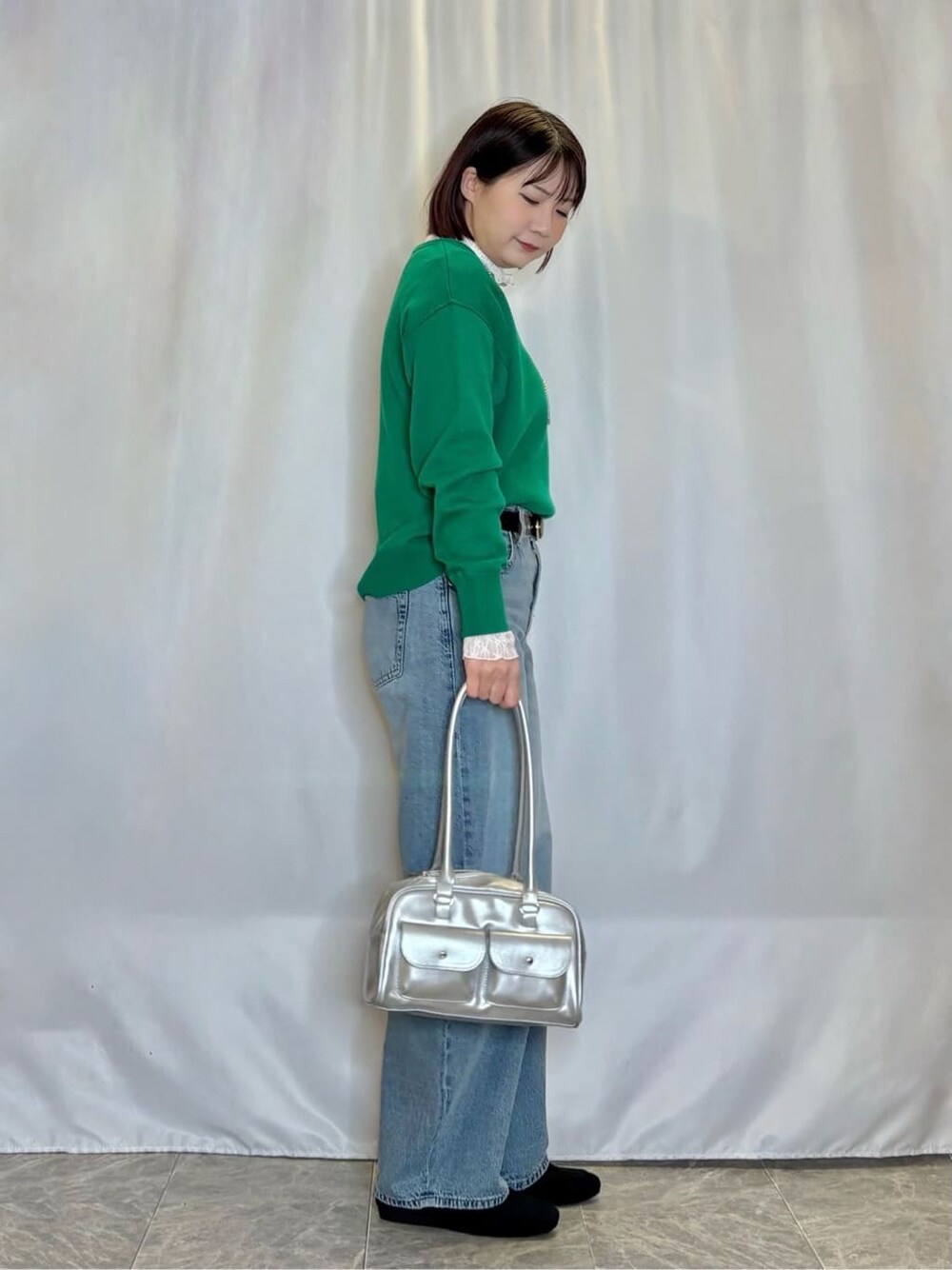 グリーン系のニット/セーター、ホワイト系のTシャツ/カットソー、ブルー系のデニムパンツを着用したレディースの冬コーディネートの2枚目の写真