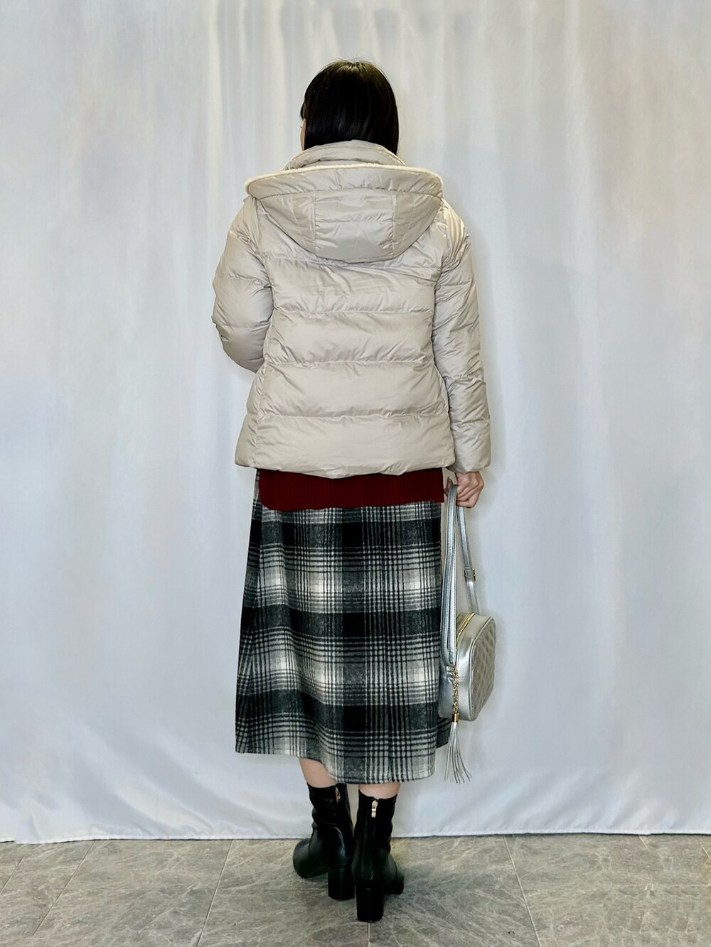 シルバー系のショルダーバッグ、レッド系のニット/セーター、ブラック系のスカートを着用したレディースの冬コーディネートの3枚目の写真