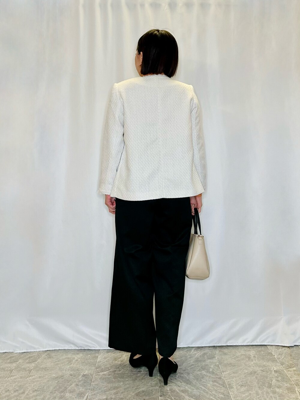 ブラック系のパンプス、ベージュ系のトートバッグ、ベージュ系のノーカラージャケットを着用したレディースの秋コーディネートの3枚目の写真