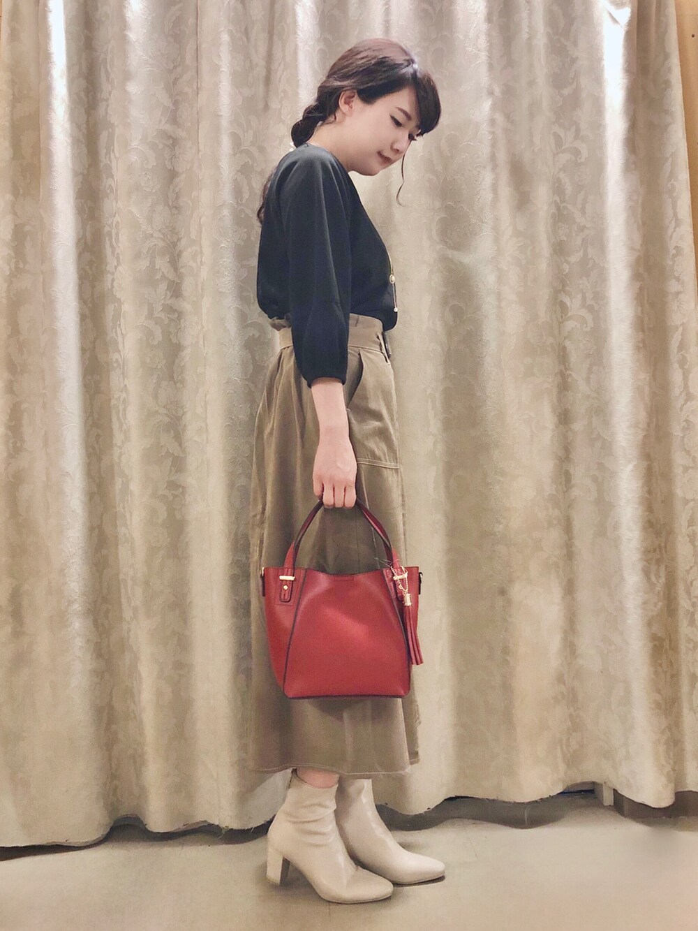 レッド系のショルダーバッグ、ホワイト系のブーツ、ベージュ系のスカートを着用したレディースの秋コーディネートの2枚目の写真