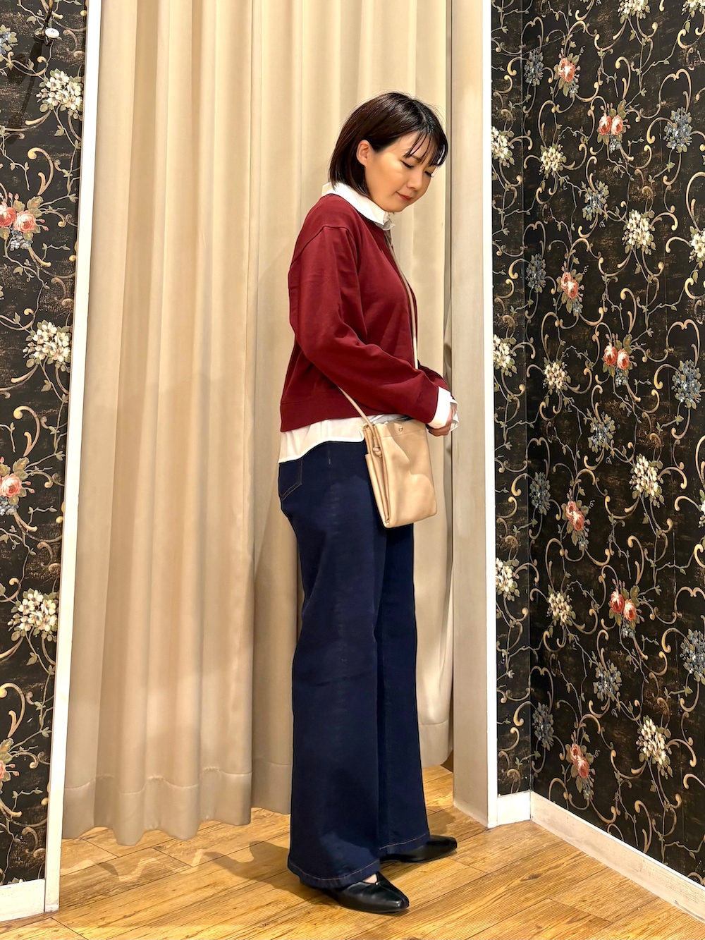 レッド系のTシャツ/カットソー、ブルー系のデニムパンツ、ベージュ系のショルダーバッグを着用したレディースの秋コーディネートの2枚目の写真