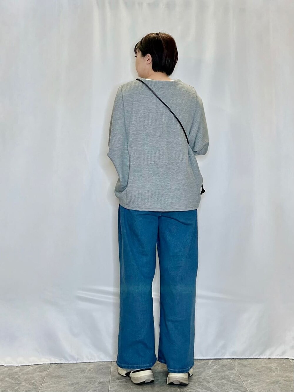 グレー系のその他トップス、ブルー系のデニムパンツ、ブラック系のショルダーバッグを着用したレディースの春コーディネートの3枚目の写真