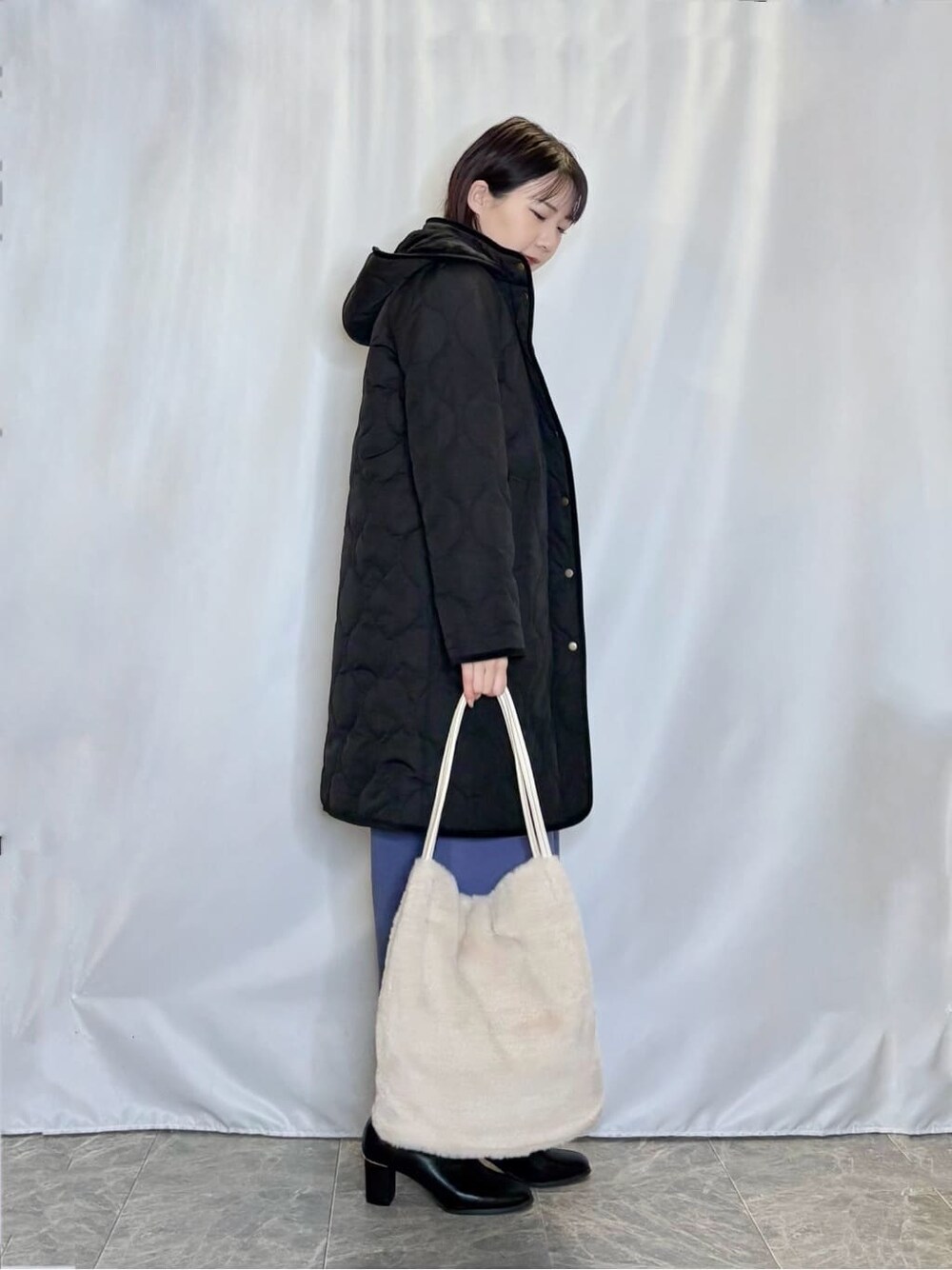 ブラック系のその他アウター、ホワイト系のニット/セーター、ブルー系のその他パンツを着用したレディースの冬コーディネートの2枚目の写真