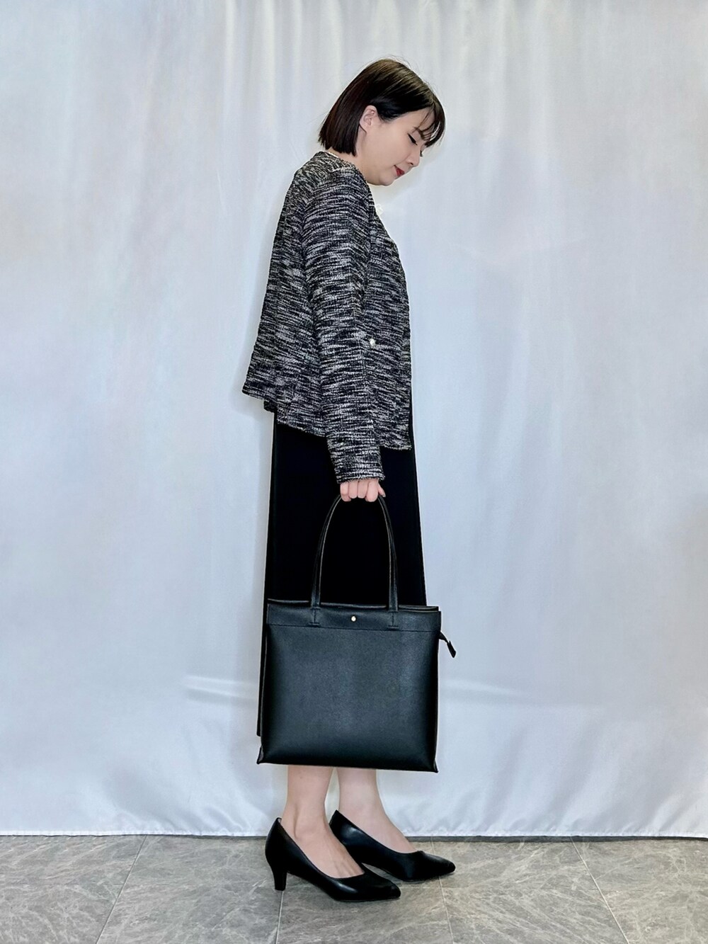ブラック系のトートバッグ、ブラック系のパンプス、ブラック系のワンピースを着用したレディースの冬コーディネートの2枚目の写真