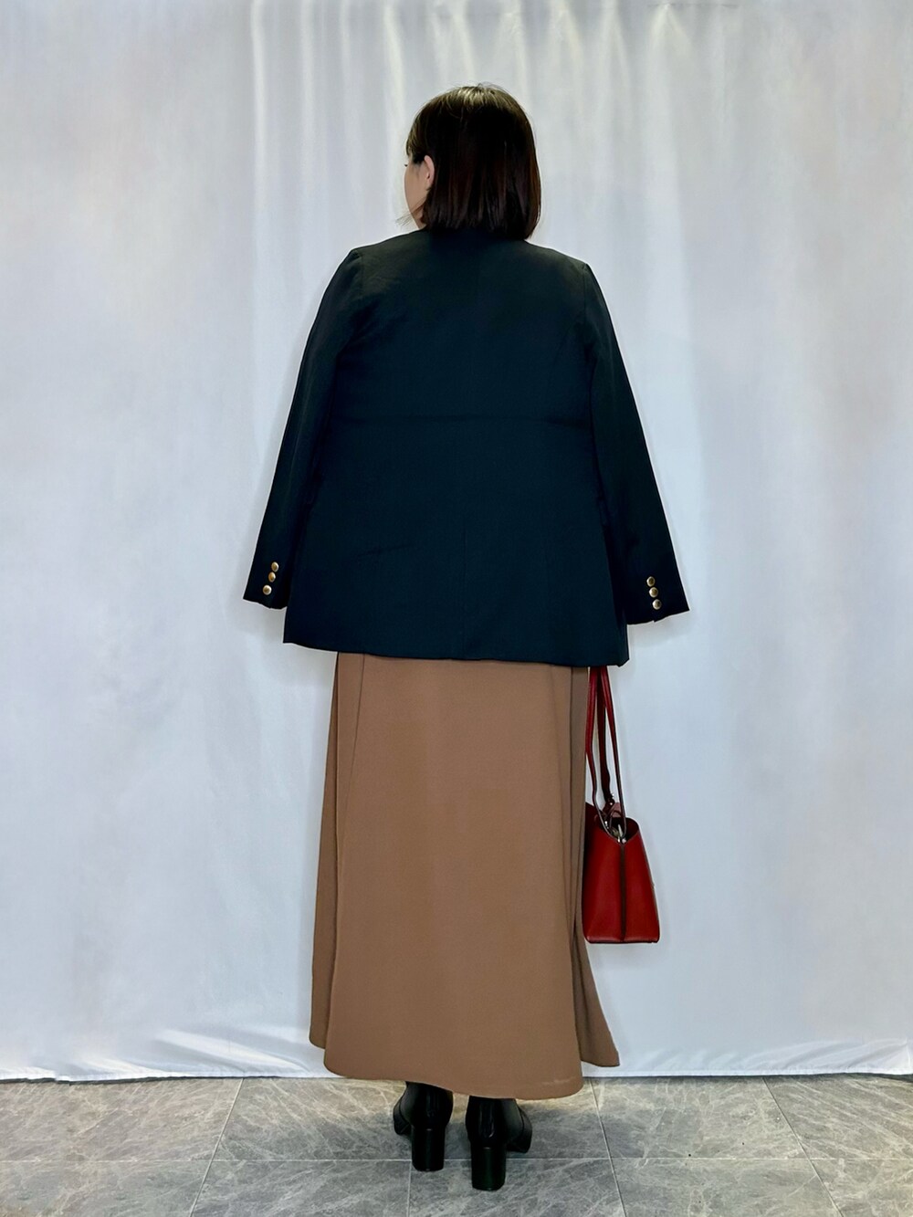 ブルー系のテーラードジャケット、レッド系のショルダーバッグ、ブラック系のブーツを着用したレディースの秋コーディネートの3枚目の写真